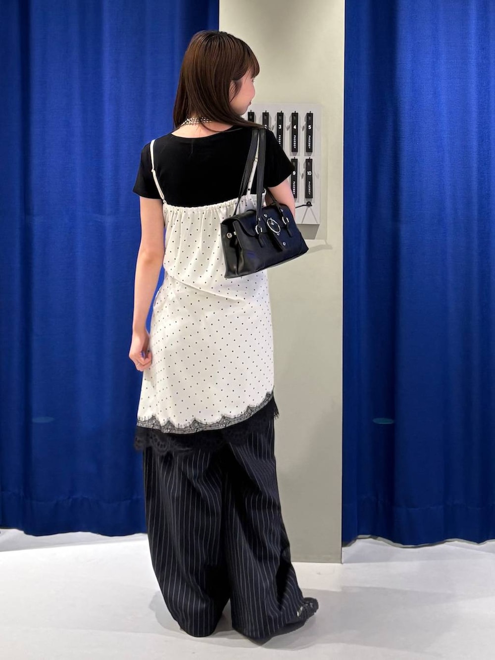 ホワイト系のチュニック、ブラック系のTシャツ/カットソー、ブラック系のショルダーバッグを着用したレディースの夏コーディネートの3枚目の写真