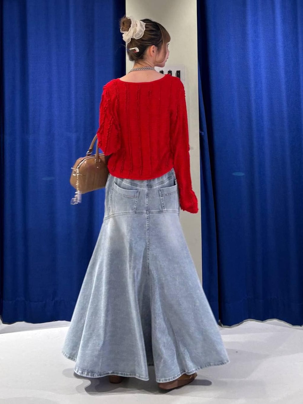 ホワイト系のキャミソール、ブラウン系のボストンバッグ、ブルー系のデニムスカートを着用したレディースの春コーディネートの3枚目の写真