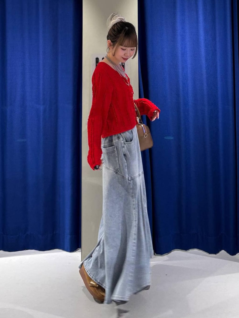 ホワイト系のキャミソール、ブラウン系のボストンバッグ、ブルー系のデニムスカートを着用したレディースの春コーディネートの2枚目の写真