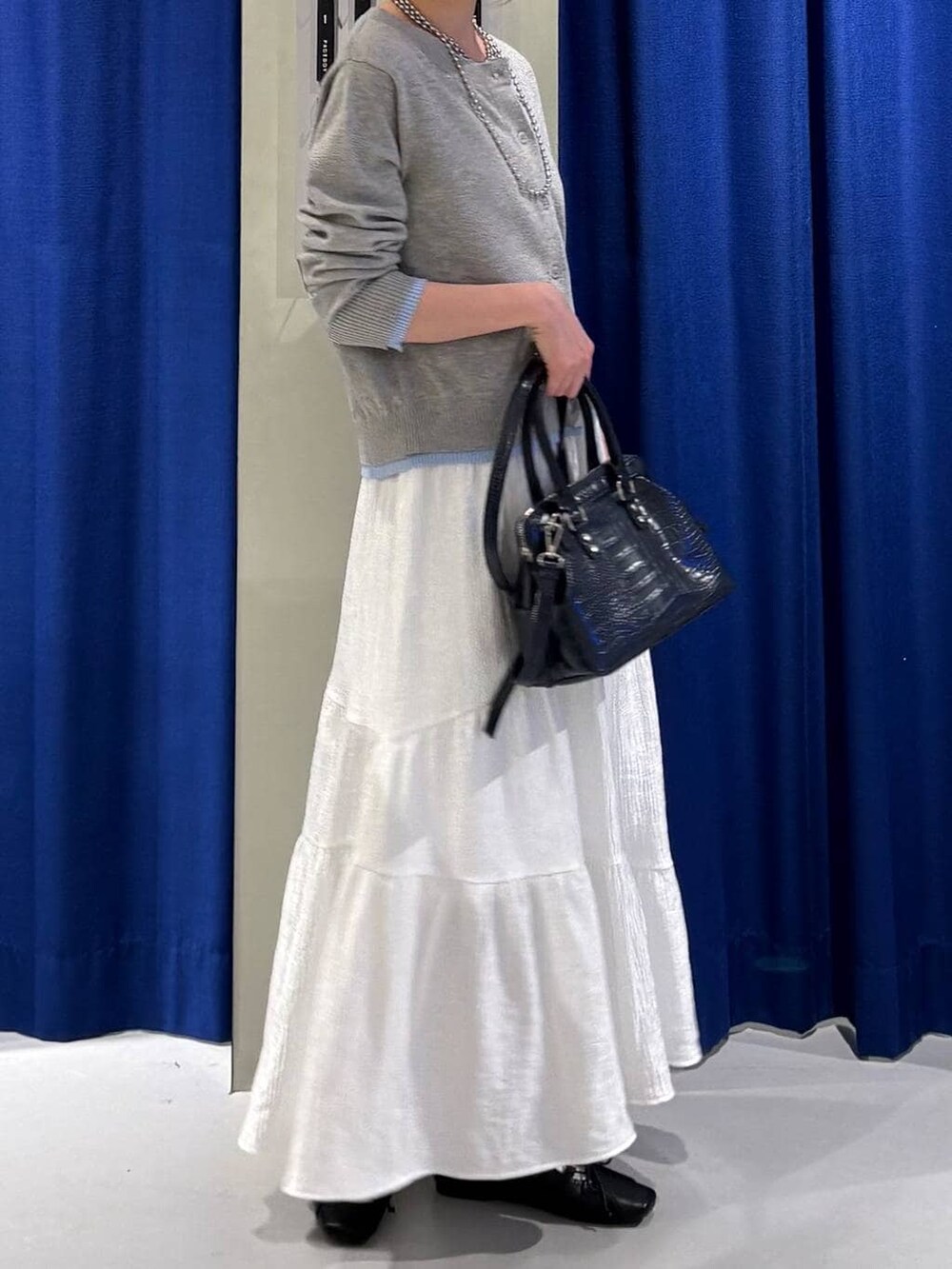 ブルー系のハンドバッグ、ブラック系のスニーカー、グレー系のカーディガン/ボレロを着用したレディースの冬コーディネートの2枚目の写真