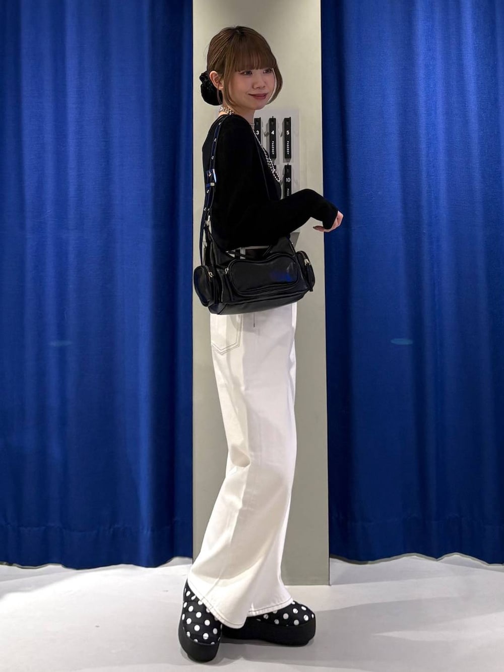 ブラック系のショルダーバッグ、ホワイト系のスラックス、ブラック系のニット/セーターを着用したレディースの冬コーディネートの2枚目の写真