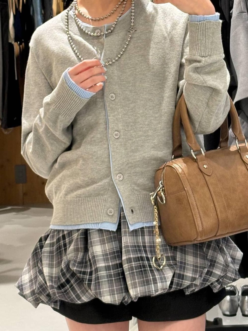 ブラック系のブーツ、ブラウン系のボストンバッグ、グレー系のカーディガン/ボレロを着用したレディースの春コーディネートの2枚目の写真