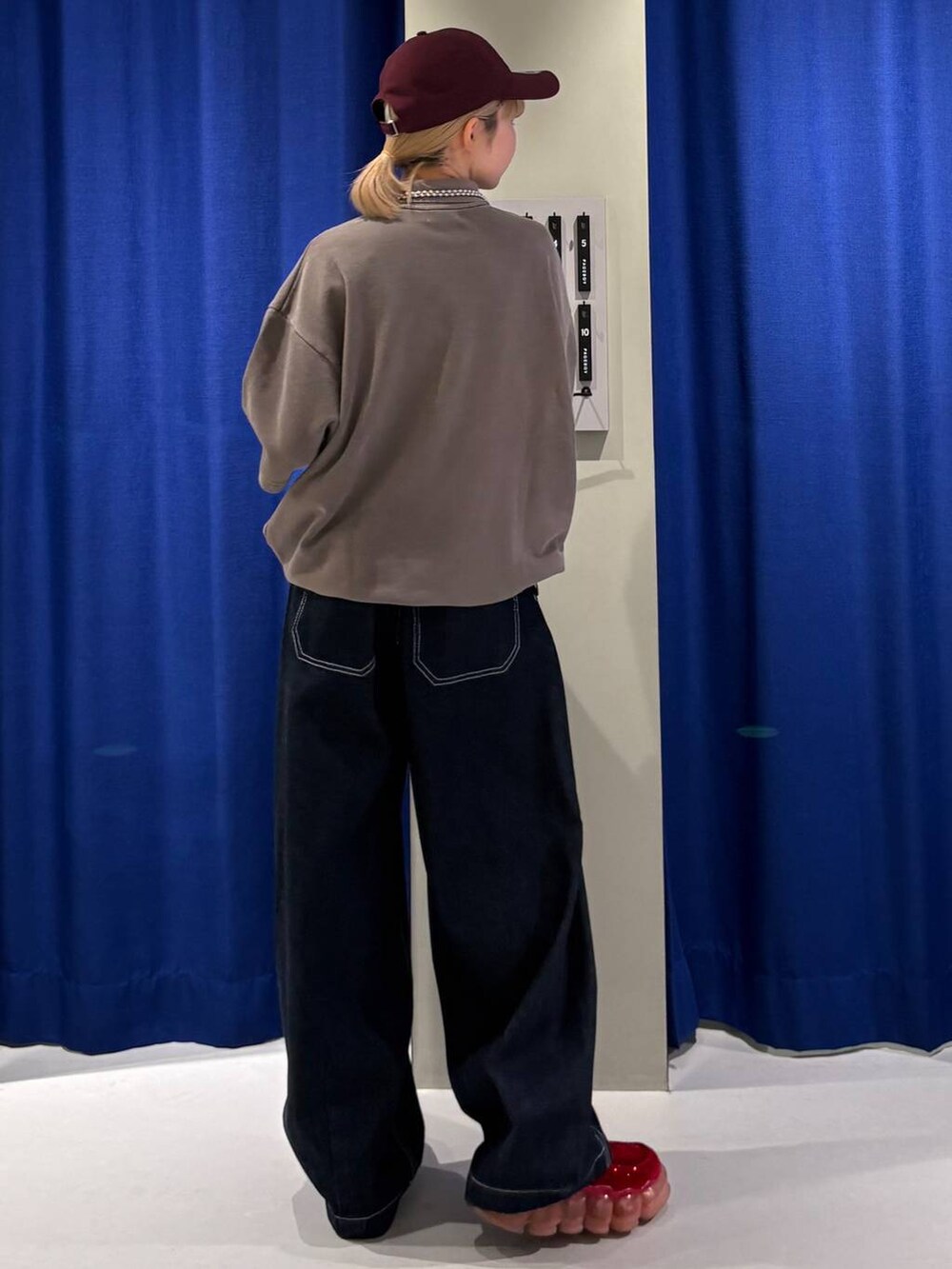 ブルー系のデニムパンツ、ブラウン系のスウェット、レッド系のキャップを着用したレディースの夏コーディネートの3枚目の写真