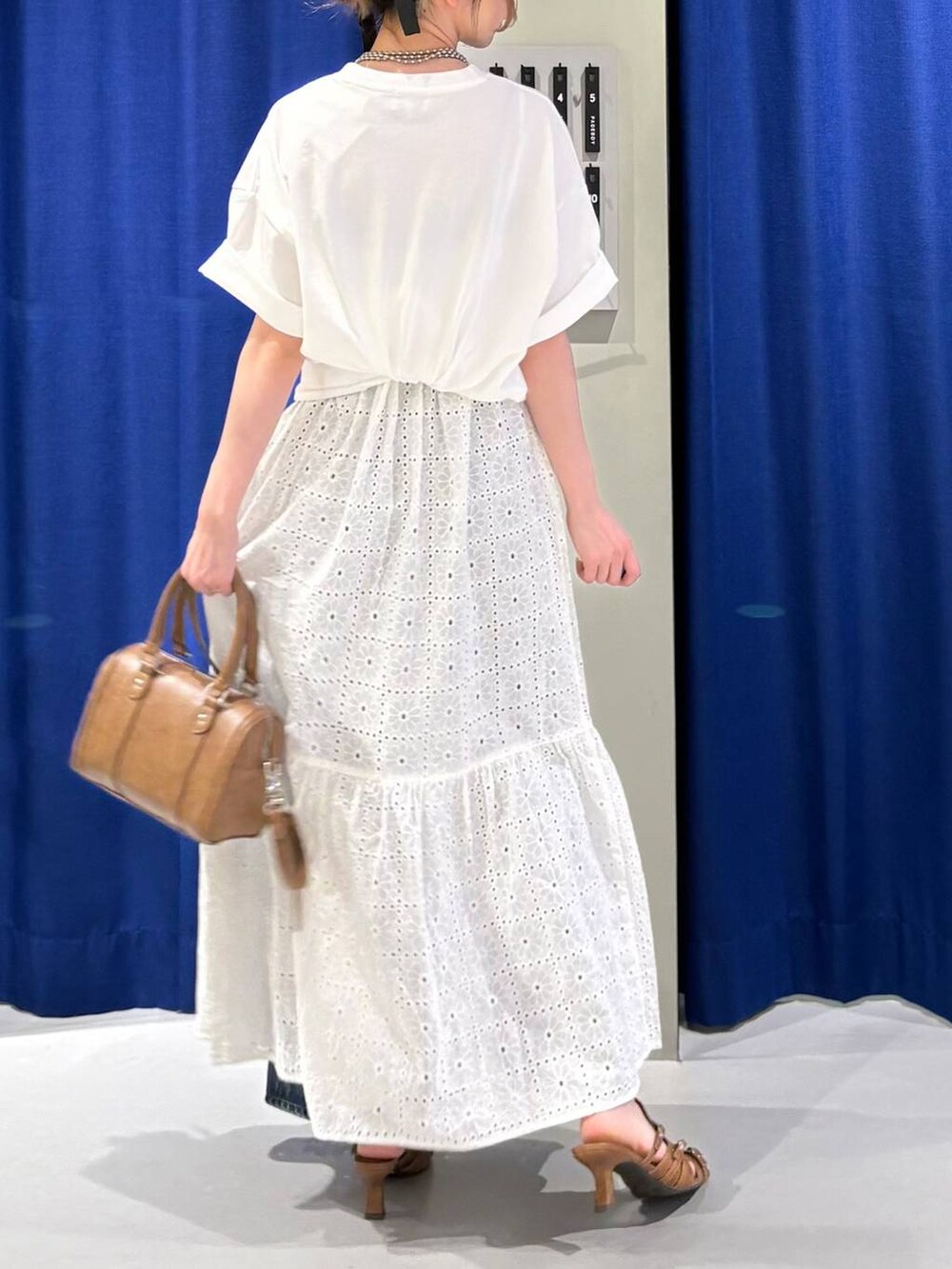 ブルー系のデニムパンツ、ブラウン系のボストンバッグ、ホワイト系のTシャツ/カットソーを着用したレディースの春コーディネートの3枚目の写真