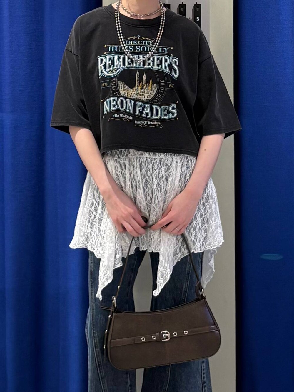 ブルー系のデニムパンツ、ブラウン系のハンドバッグ、グレー系のTシャツ/カットソーを着用したレディースの春コーディネートの4枚目の写真