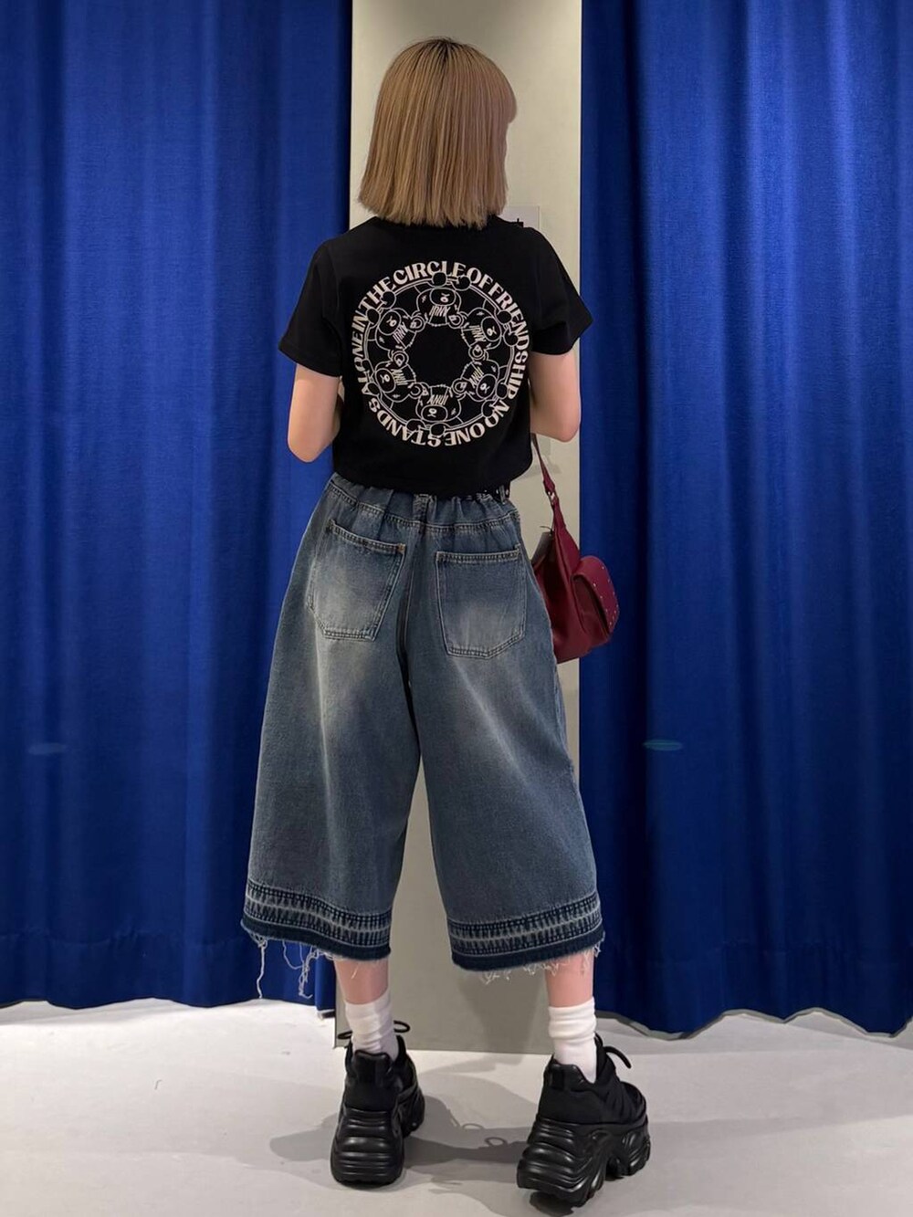 ブラック系のスニーカー、ブラック系のTシャツ/カットソー、ブルー系のデニムパンツを着用したレディースの夏コーディネートの3枚目の写真