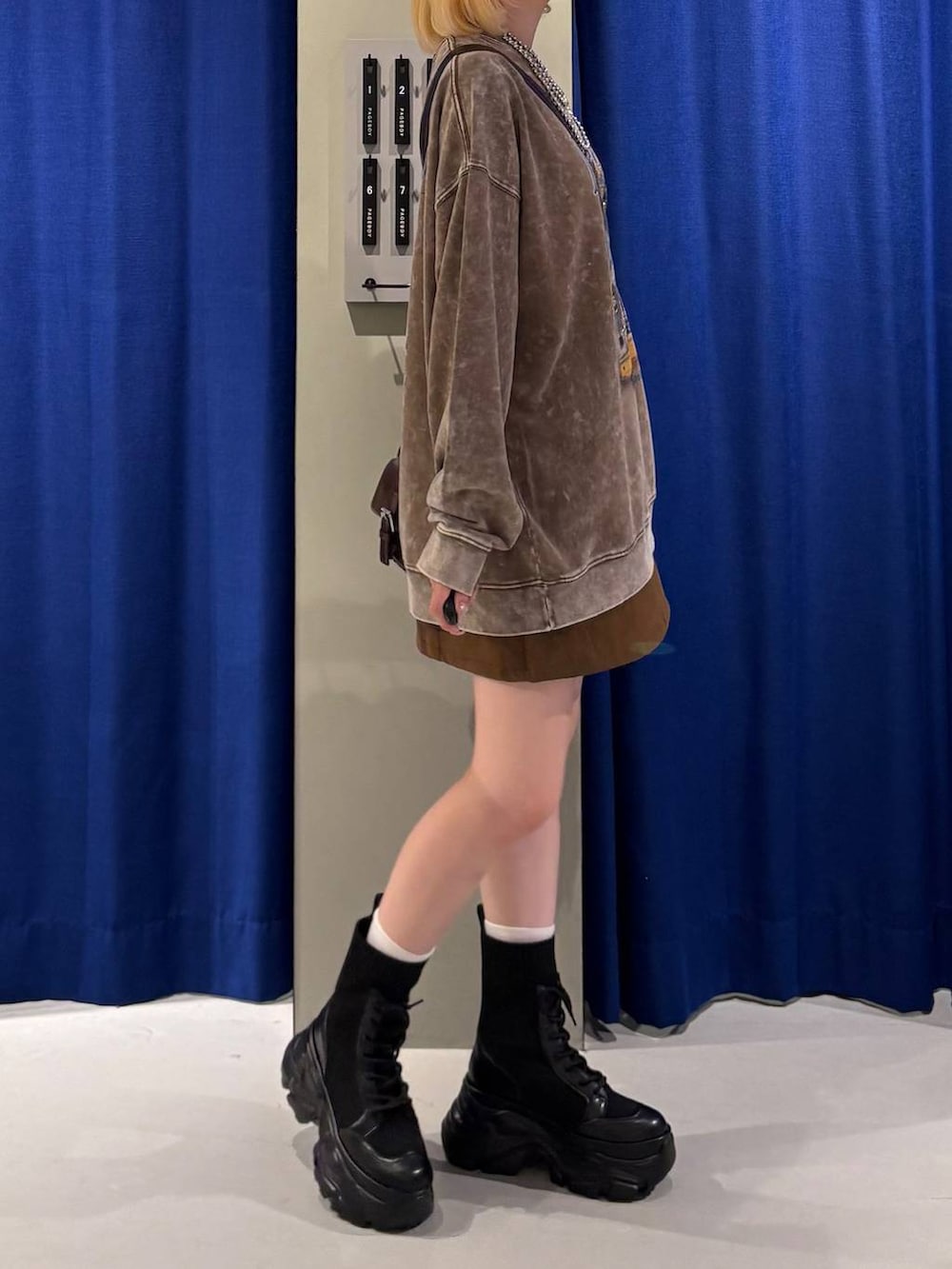 ブラック系のブーツ、ブラウン系のショルダーバッグ、ブラック系のスカートを着用したレディースの秋コーディネートの2枚目の写真