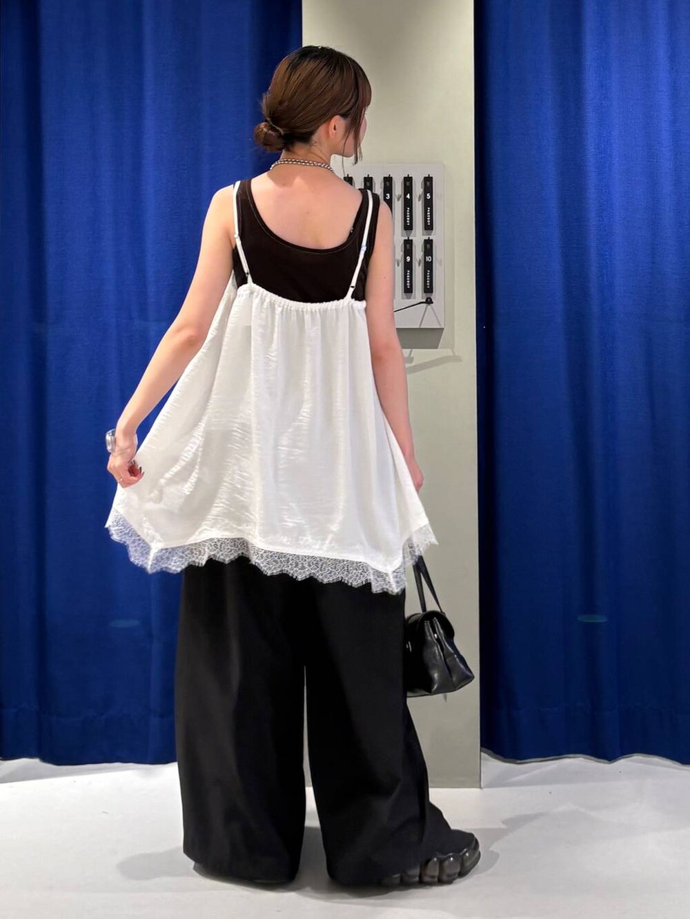ブラック系のスラックス、ブラウン系のタンクトップ、ホワイト系のキャミソールを着用したレディースの夏コーディネートの3枚目の写真