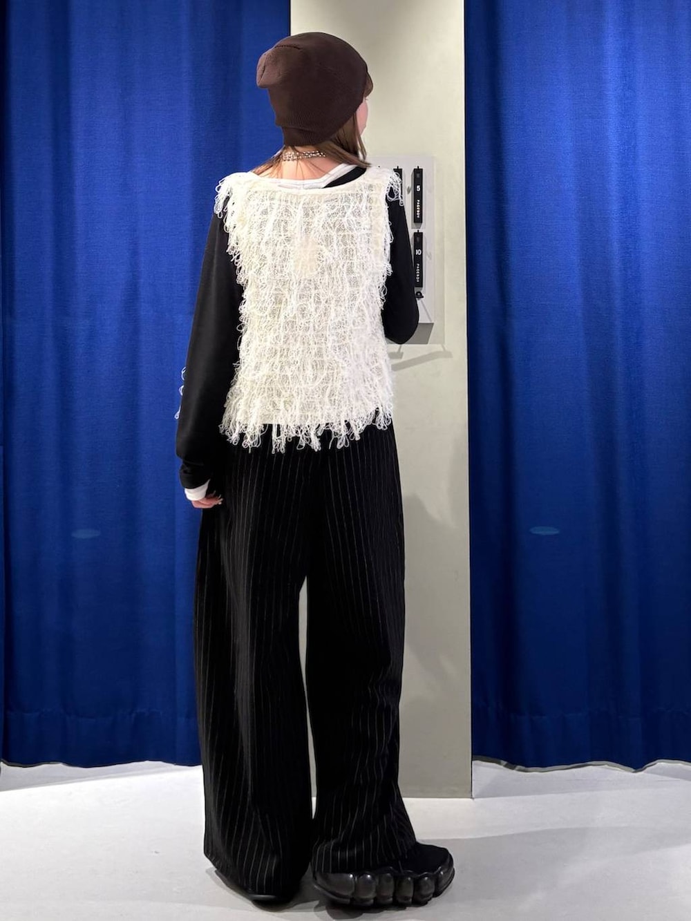 ブラック系のスラックス、ホワイト系のベスト、ブラック系のTシャツ/カットソーを着用したレディースの冬コーディネートの3枚目の写真