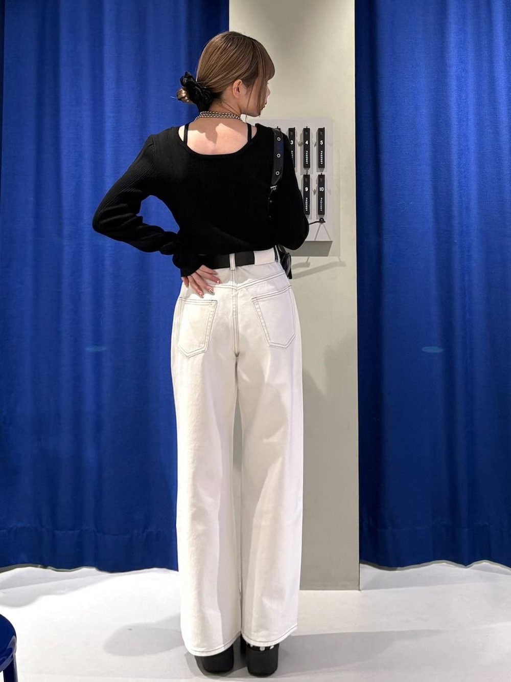 ブラック系のショルダーバッグ、ホワイト系のスラックス、ブラック系のニット/セーターを着用したレディースの冬コーディネートの3枚目の写真