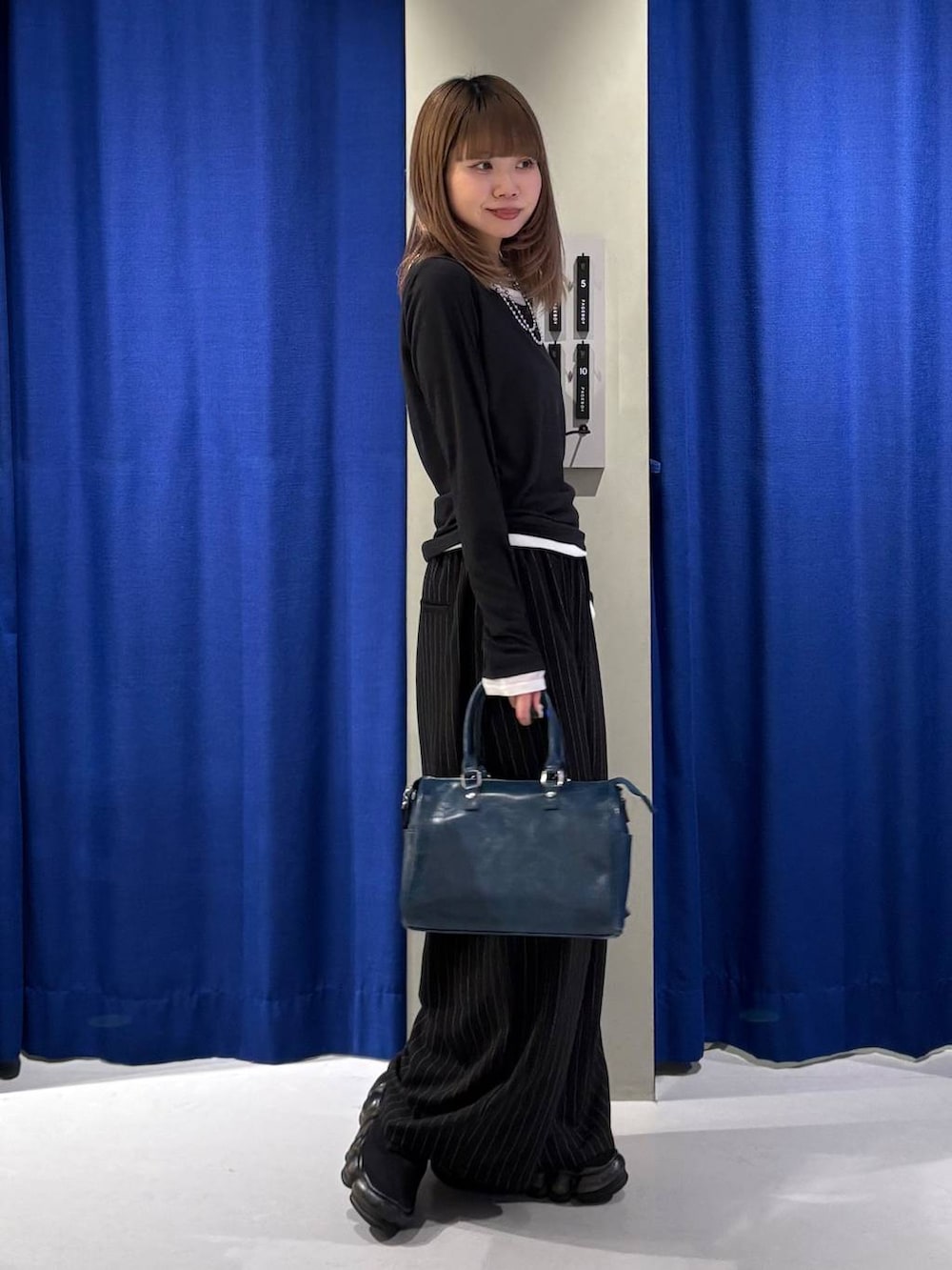 グレー系のショルダーバッグ、ブラック系のスラックス、ブラック系のTシャツ/カットソーを着用したレディースの冬コーディネートの2枚目の写真