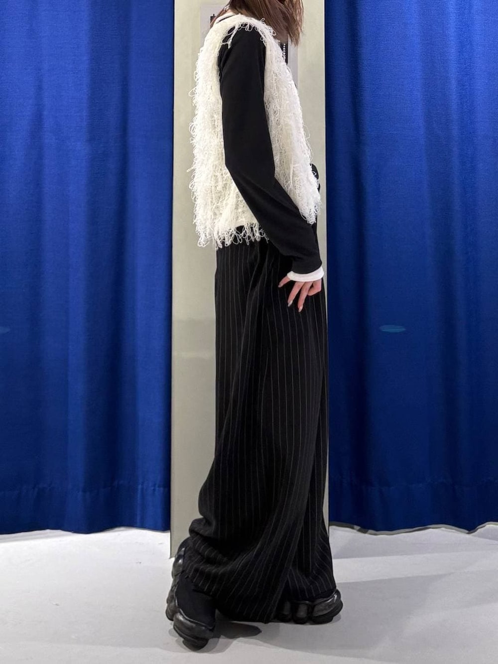 ブラック系のスラックス、ホワイト系のベスト、ブラック系のTシャツ/カットソーを着用したレディースの冬コーディネートの2枚目の写真