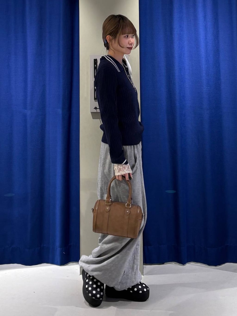 ホワイト系のTシャツ/カットソー、ブラウン系のボストンバッグ、ブルー系のニット/セーターを着用したレディースの冬コーディネートの2枚目の写真