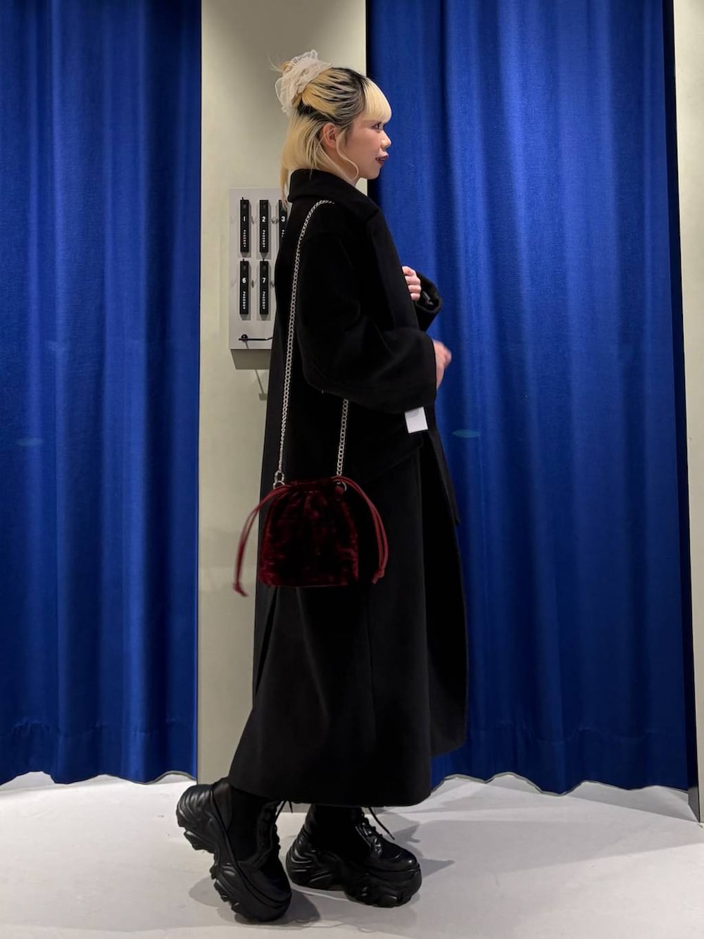 ブラック系のブーツ、ブラック系のチェスターコート、グレー系のニット/セーターを着用したレディースの冬コーディネートの2枚目の写真