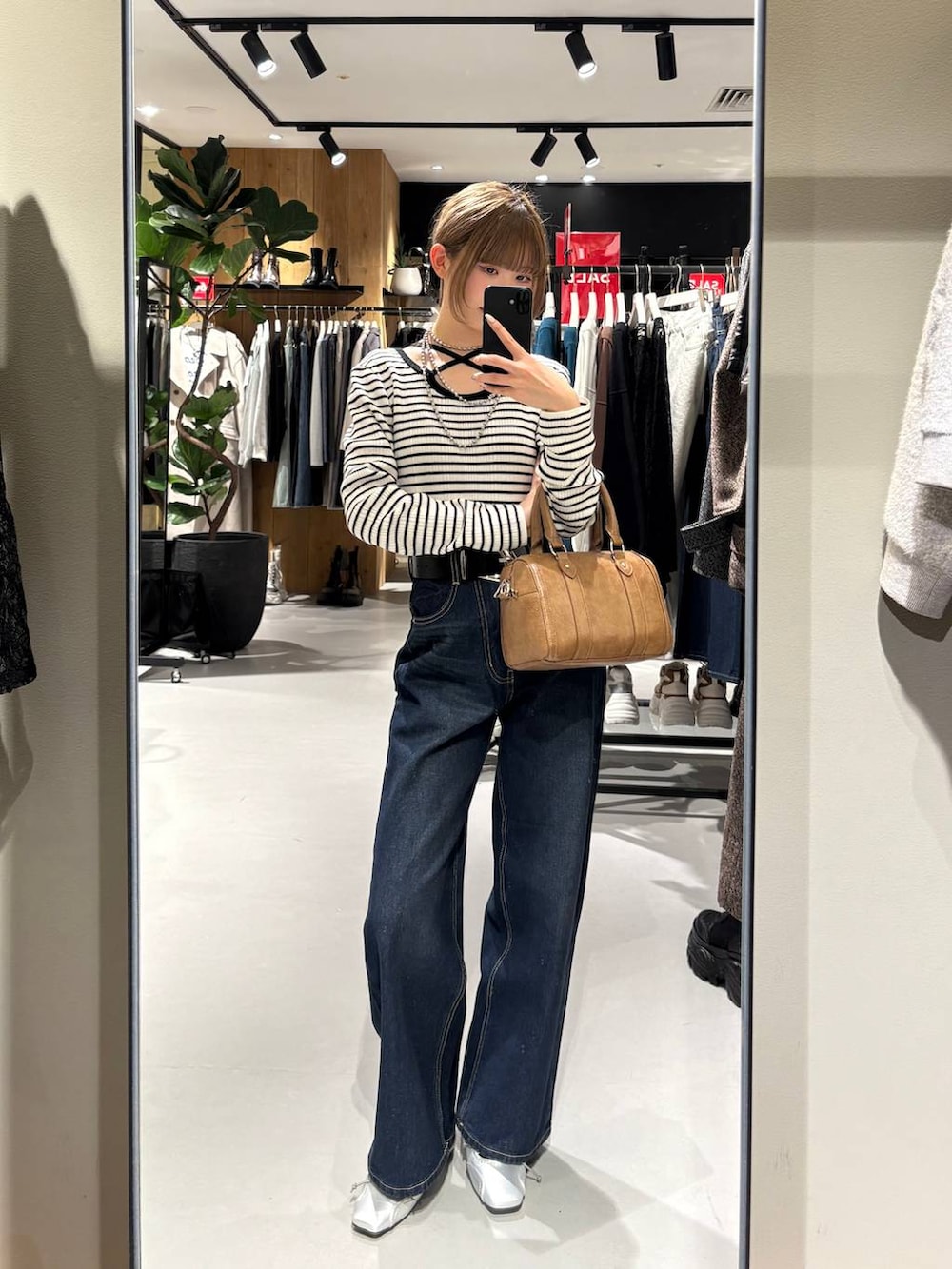 ブルー系のスラックス、ブラウン系のボストンバッグ、ホワイト系のニット/セーターを着用したレディースの冬コーディネートの5枚目の写真