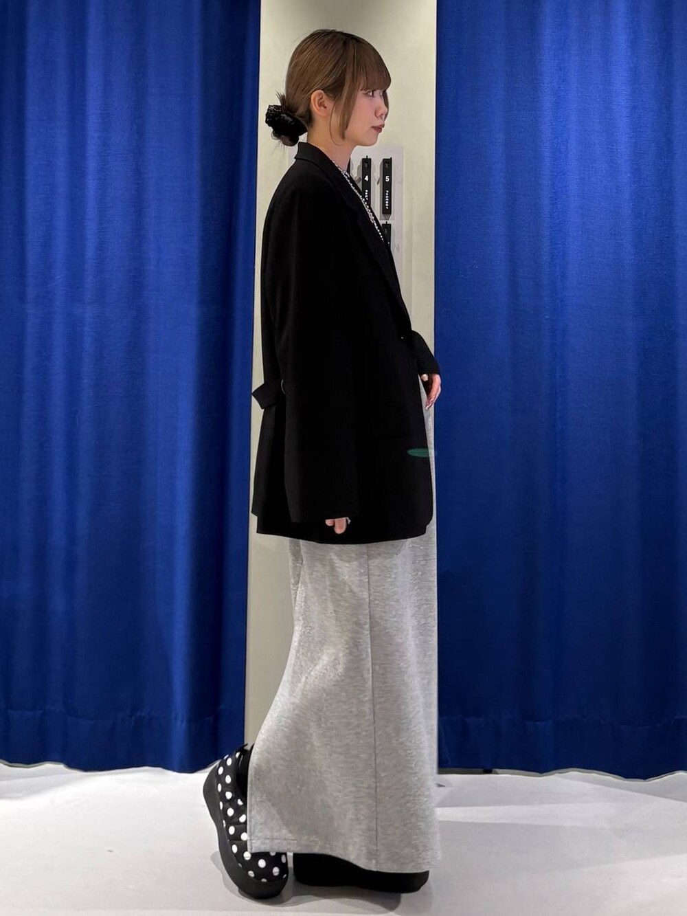 グレー系のスカート、ブラック系のニット/セーター、ブラック系のテーラードジャケットを着用したレディースの冬コーディネートの2枚目の写真