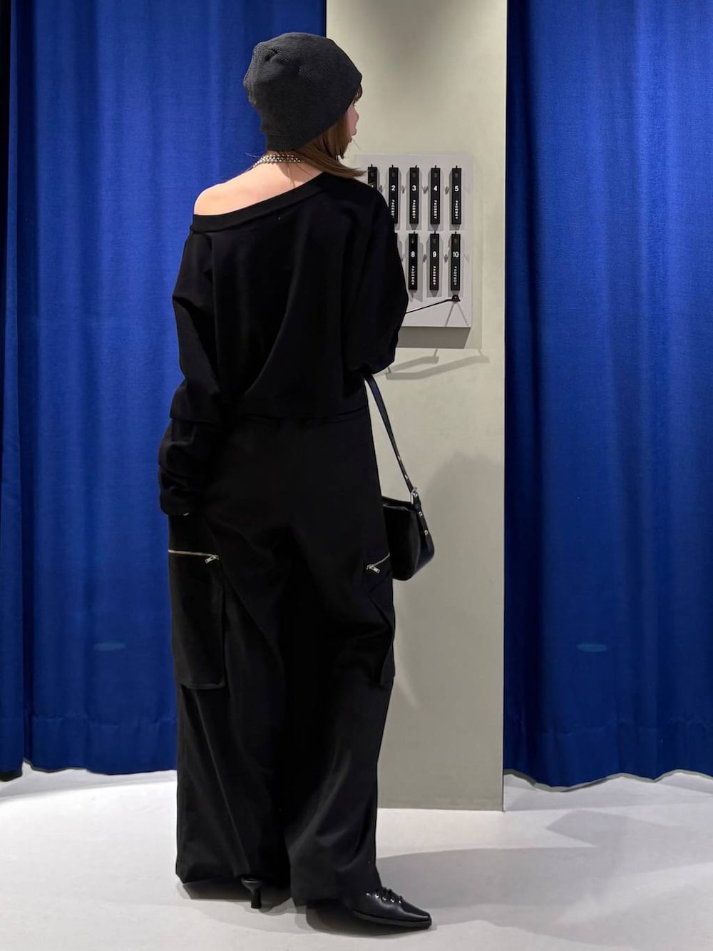 ブラック系のハンドバッグ、ブラック系のニット/セーター、ブラック系のスラックスを着用したレディースの冬コーディネートの3枚目の写真