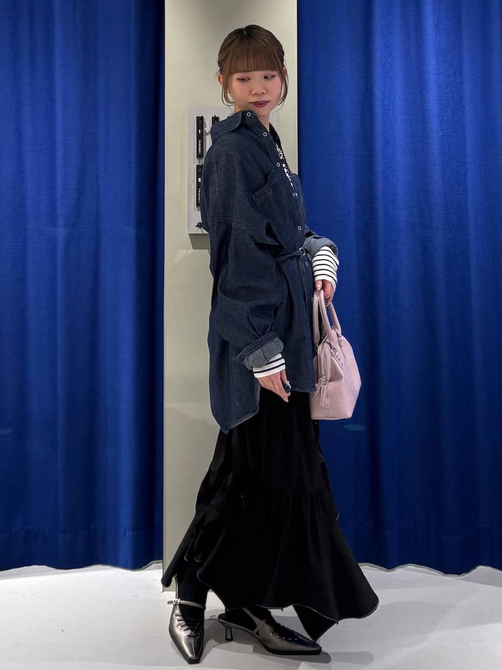 ブラック系のスカート、ピンク系のハンドバッグ、ブルー系のシャツ/ブラウスを着用したレディースの冬コーディネートの2枚目の写真