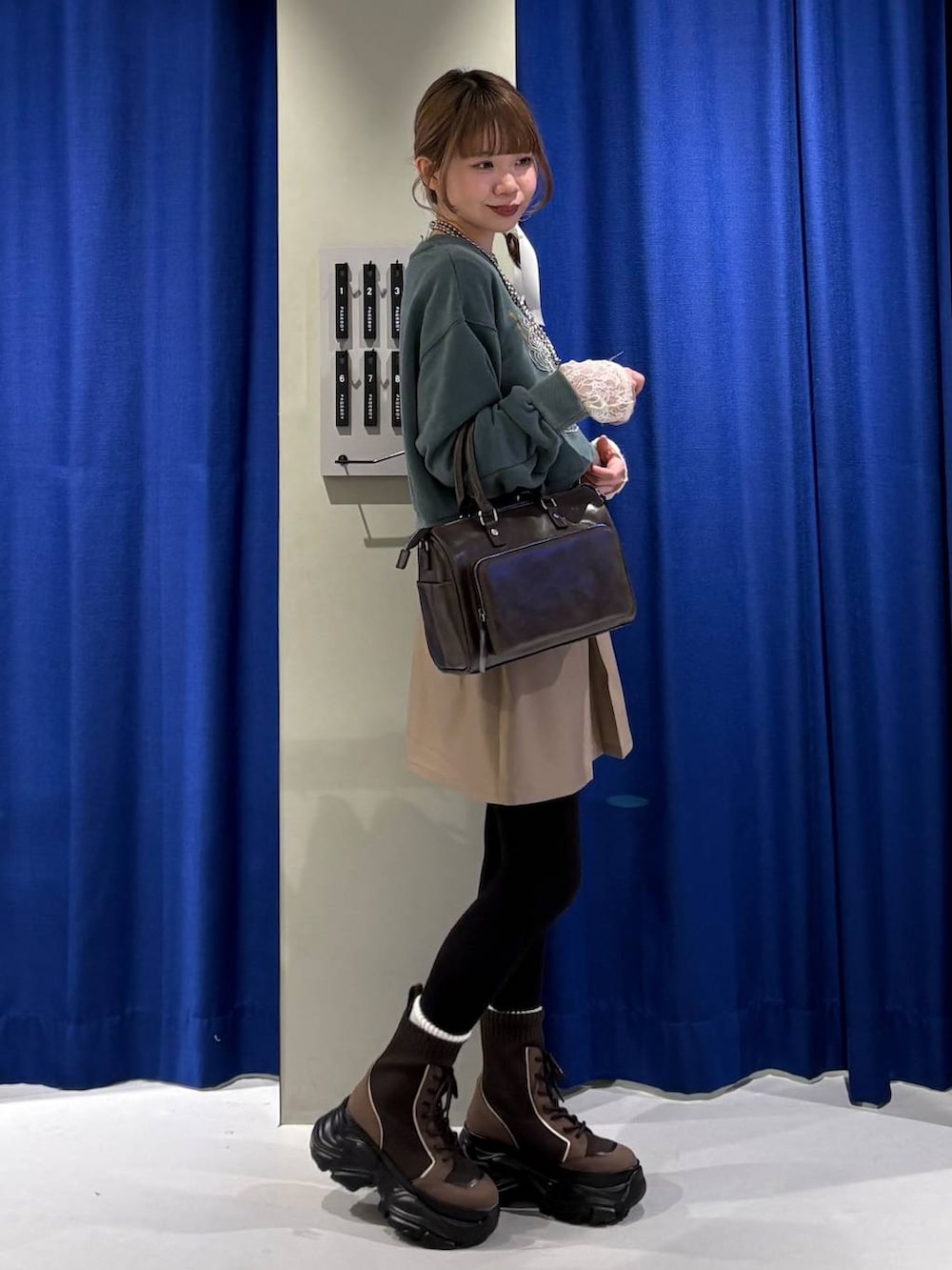 ブラウン系のブーツ、ホワイト系のTシャツ/カットソー、グリーン系のスウェットを着用したレディースの冬コーディネートの2枚目の写真