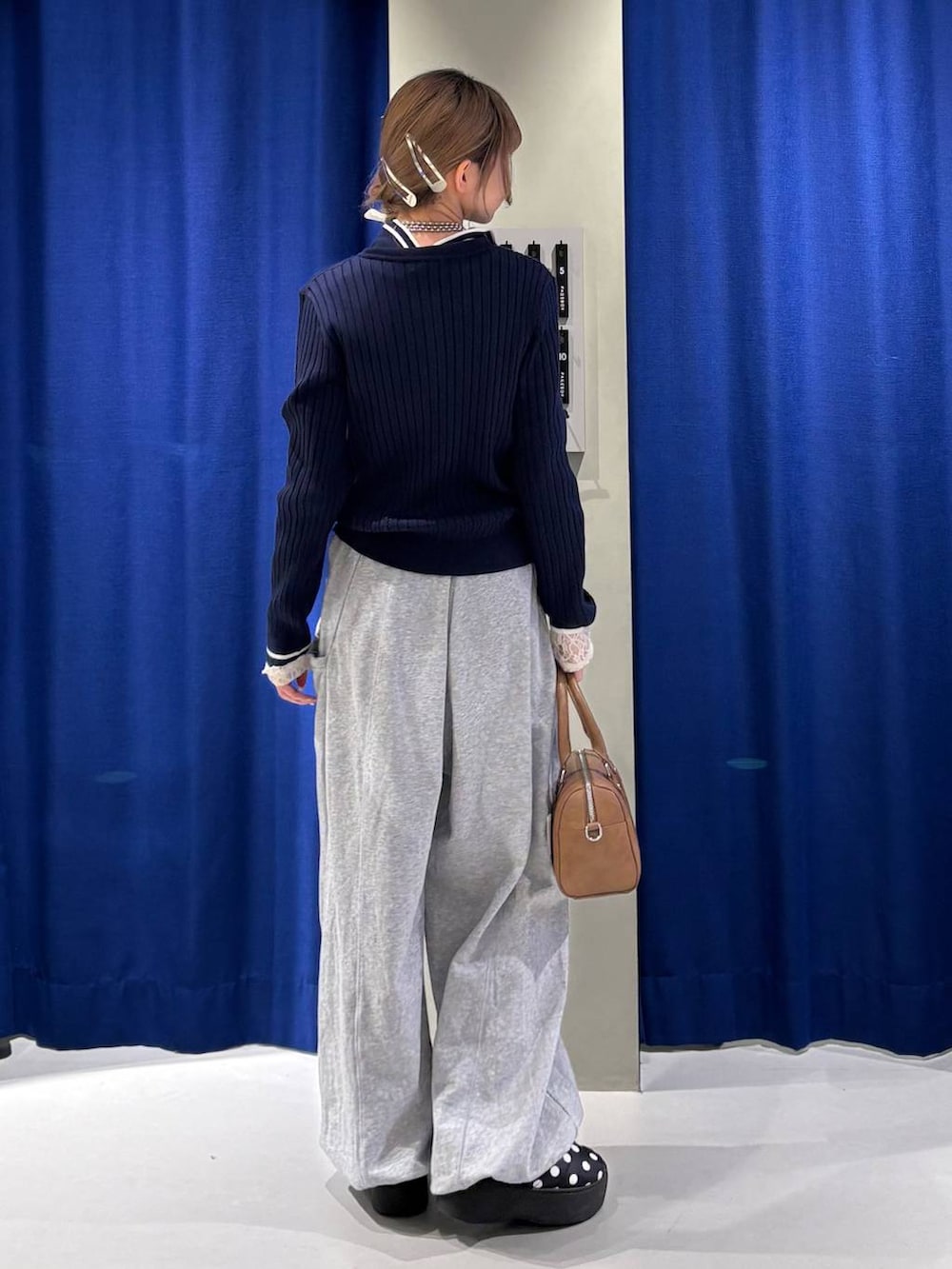 ホワイト系のTシャツ/カットソー、ブラウン系のボストンバッグ、ブルー系のニット/セーターを着用したレディースの冬コーディネートの3枚目の写真