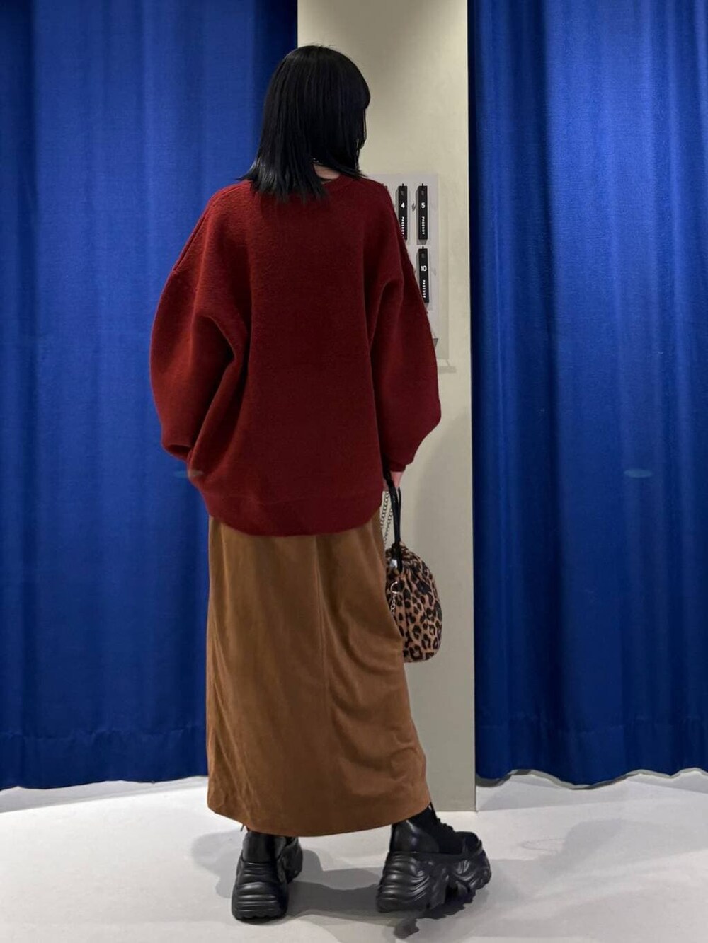 ブラック系のブーツ、ブラック系のハンドバッグ、イエロー系のスカートを着用したレディースの冬コーディネートの3枚目の写真