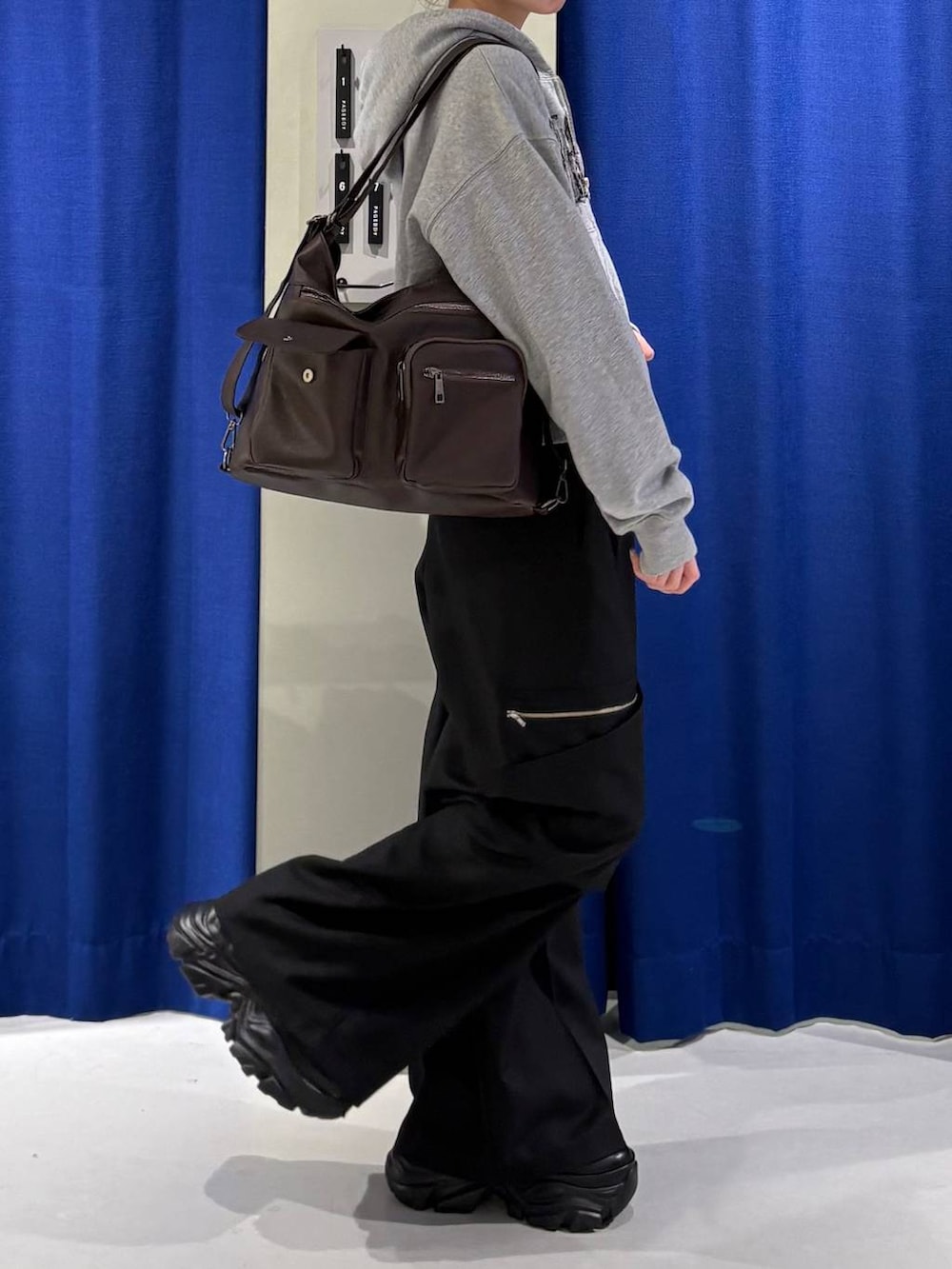 ブラック系のスニーカー、ブラウン系のショルダーバッグ、グレー系のパーカーを着用したレディースの冬コーディネートの2枚目の写真