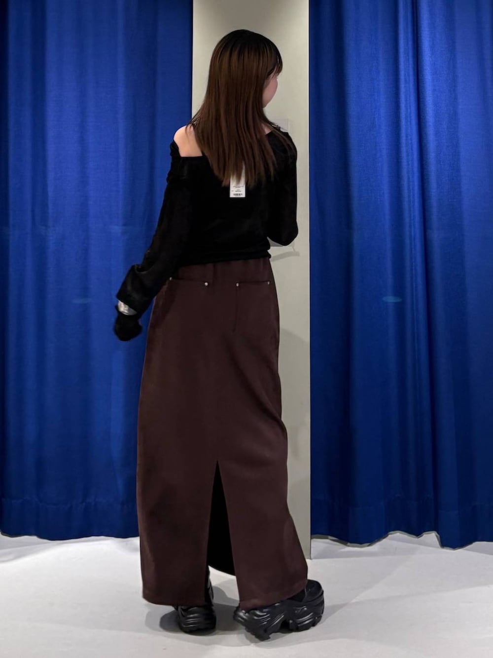 ブラウン系のスカート、ブラック系のTシャツ/カットソー、ブラック系のブーツを着用したレディースの秋コーディネートの3枚目の写真