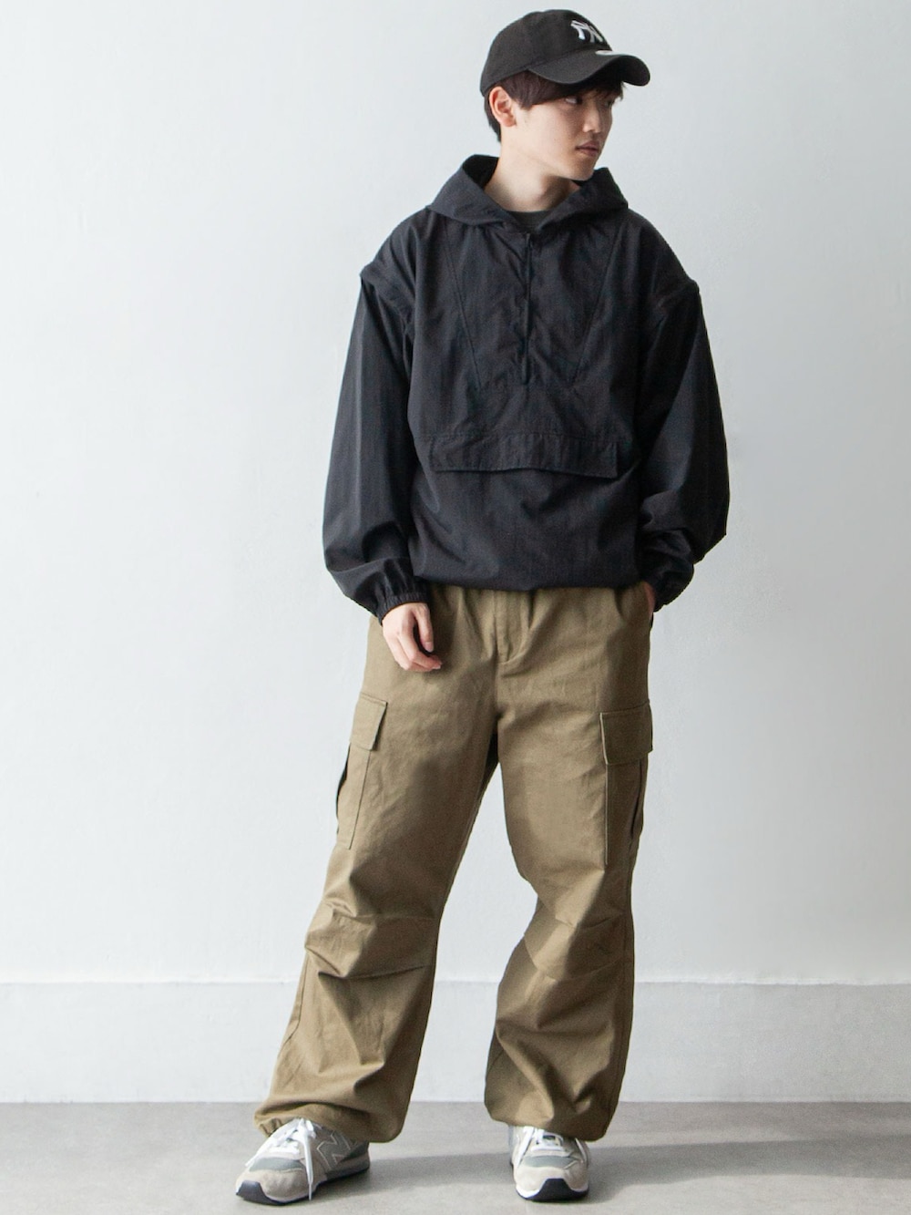 ブラック系のナイロンジャケット、グリーン系のカーゴパンツ、グレー系のスニーカーを着用したメンズの春コーディネートの2枚目の写真
