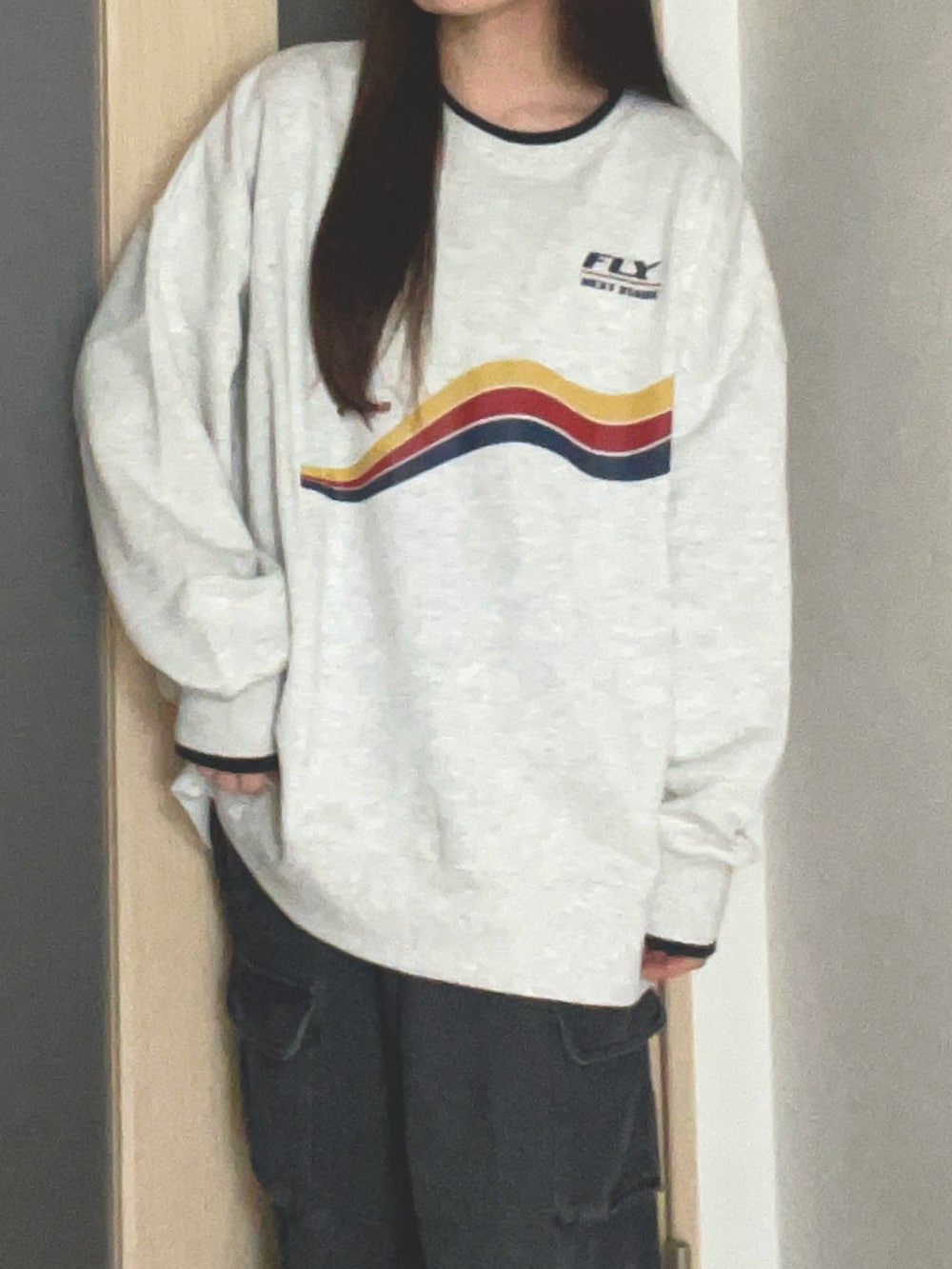 グレー系のスウェット、ブラック系のデニムパンツを着用したレディースの冬コーディネートの2枚目の写真