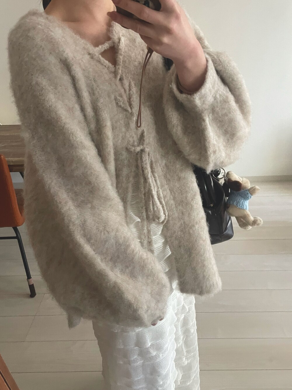 ブラウン系のショルダーバッグ、ベージュ系のニット/セーター、ホワイト系のスカートを着用したレディースの冬コーディネートの2枚目の写真