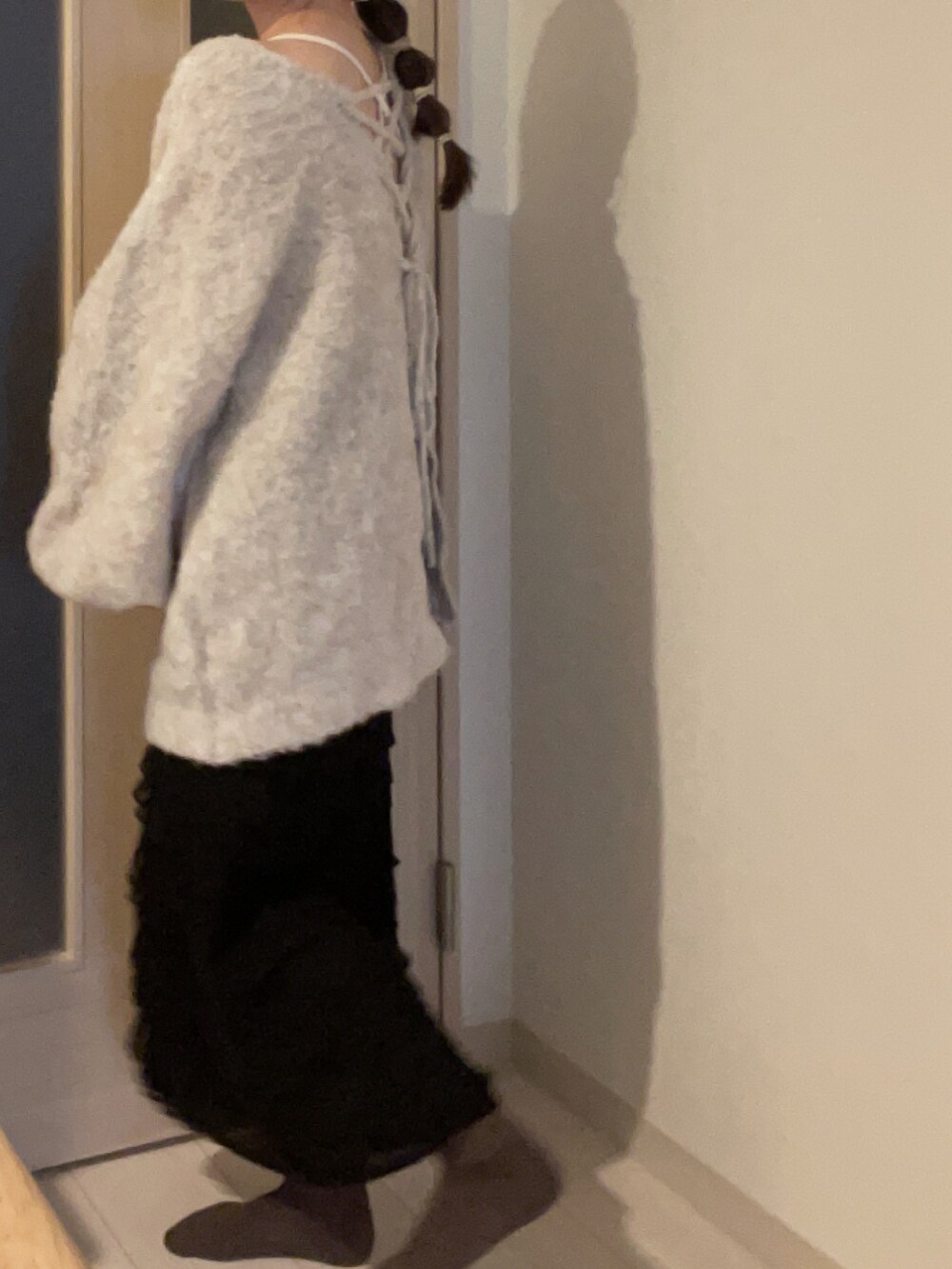 ベージュ系のニット/セーター、ブラック系のスカート、ホワイト系のキャミソールを着用したレディースの春コーディネートの2枚目の写真