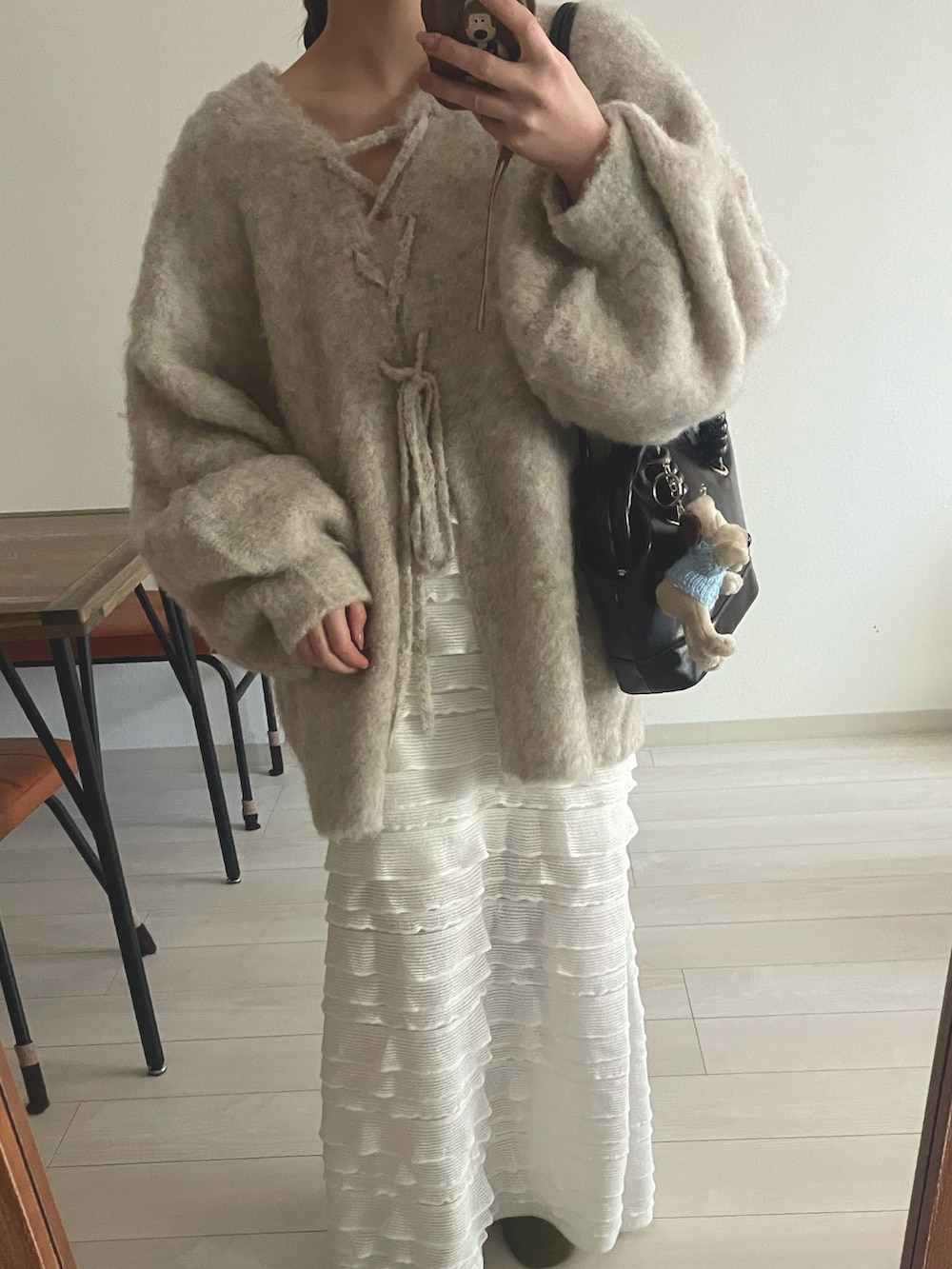 ブラウン系のショルダーバッグ、ベージュ系のニット/セーター、ホワイト系のスカートを着用したレディースの冬コーディネートの3枚目の写真