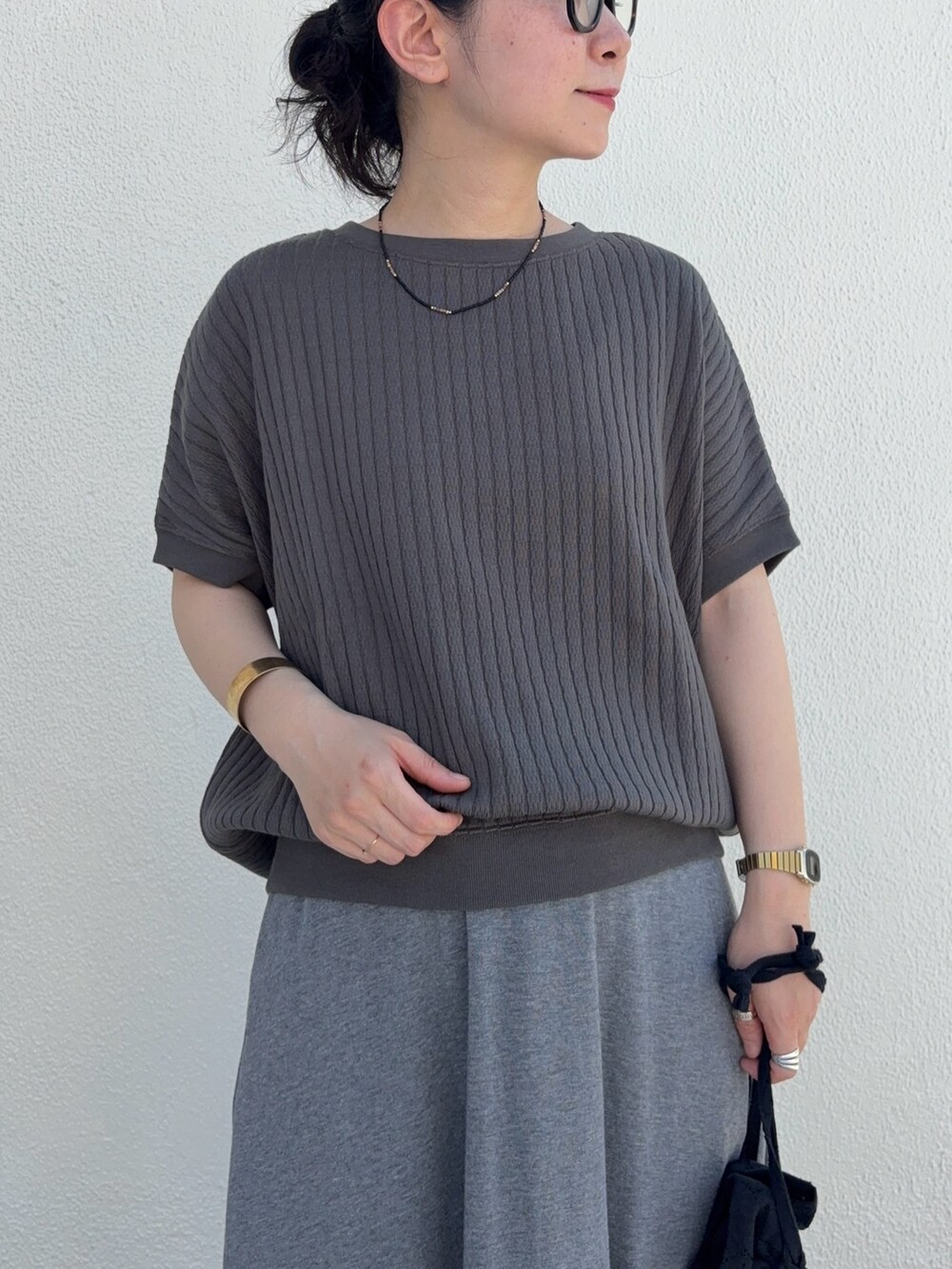 グレー系のTシャツ/カットソー、グレー系のスカート、ブラック系のサンダルを着用したレディースの夏コーディネートの4枚目の写真
