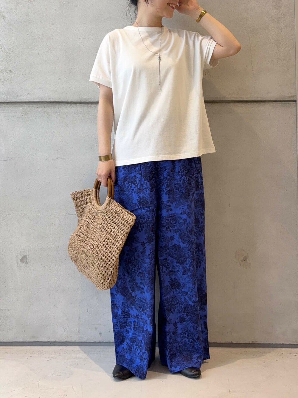 ベージュ系のトートバッグ、ブラック系のパンプス、ホワイト系のTシャツ/カットソーを着用したレディースの夏コーディネートの5枚目の写真