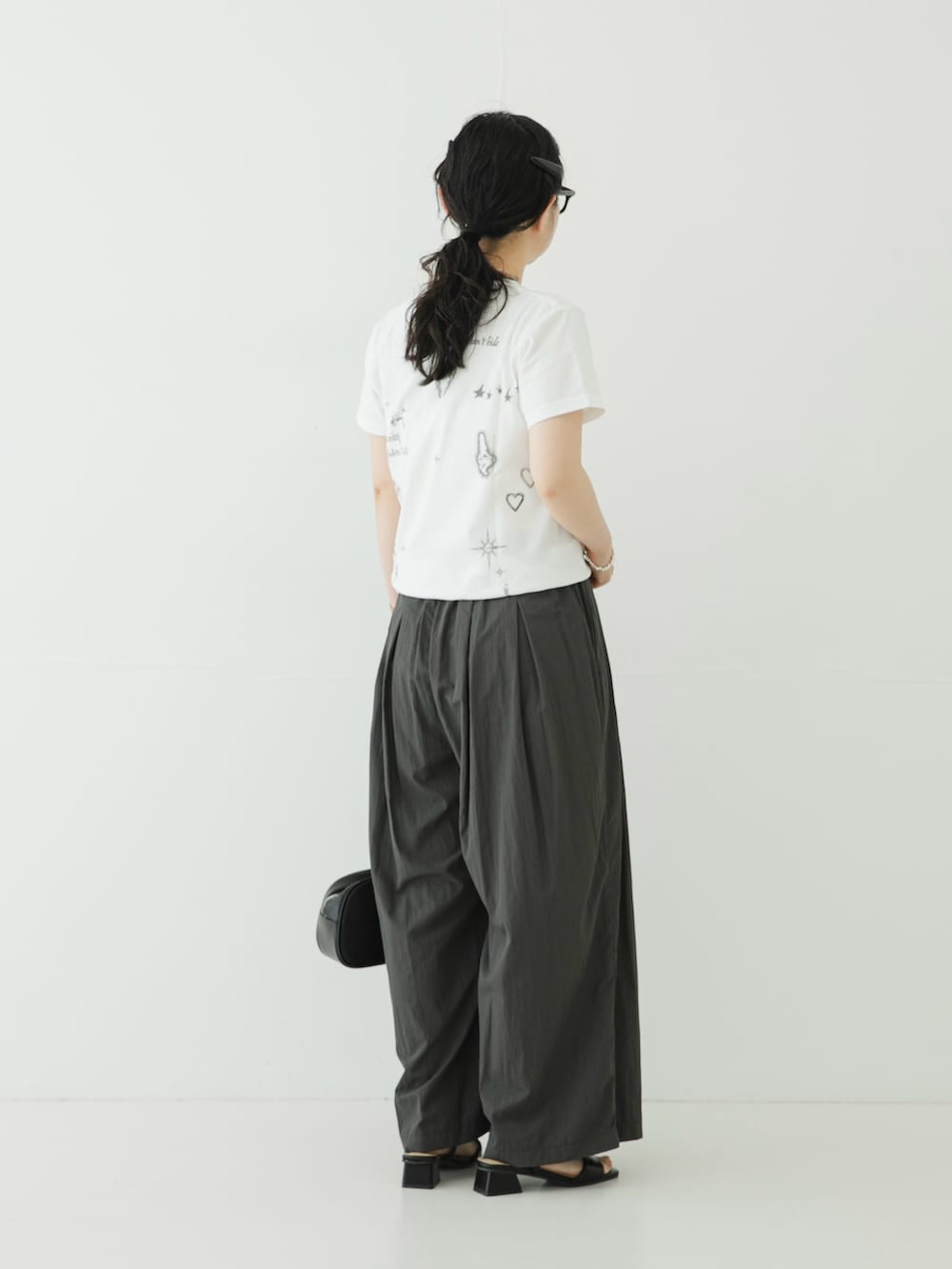 ホワイト系のTシャツ/カットソー、グレー系のその他パンツ、ブラック系のサンダルを着用したレディースの夏コーディネートの4枚目の写真