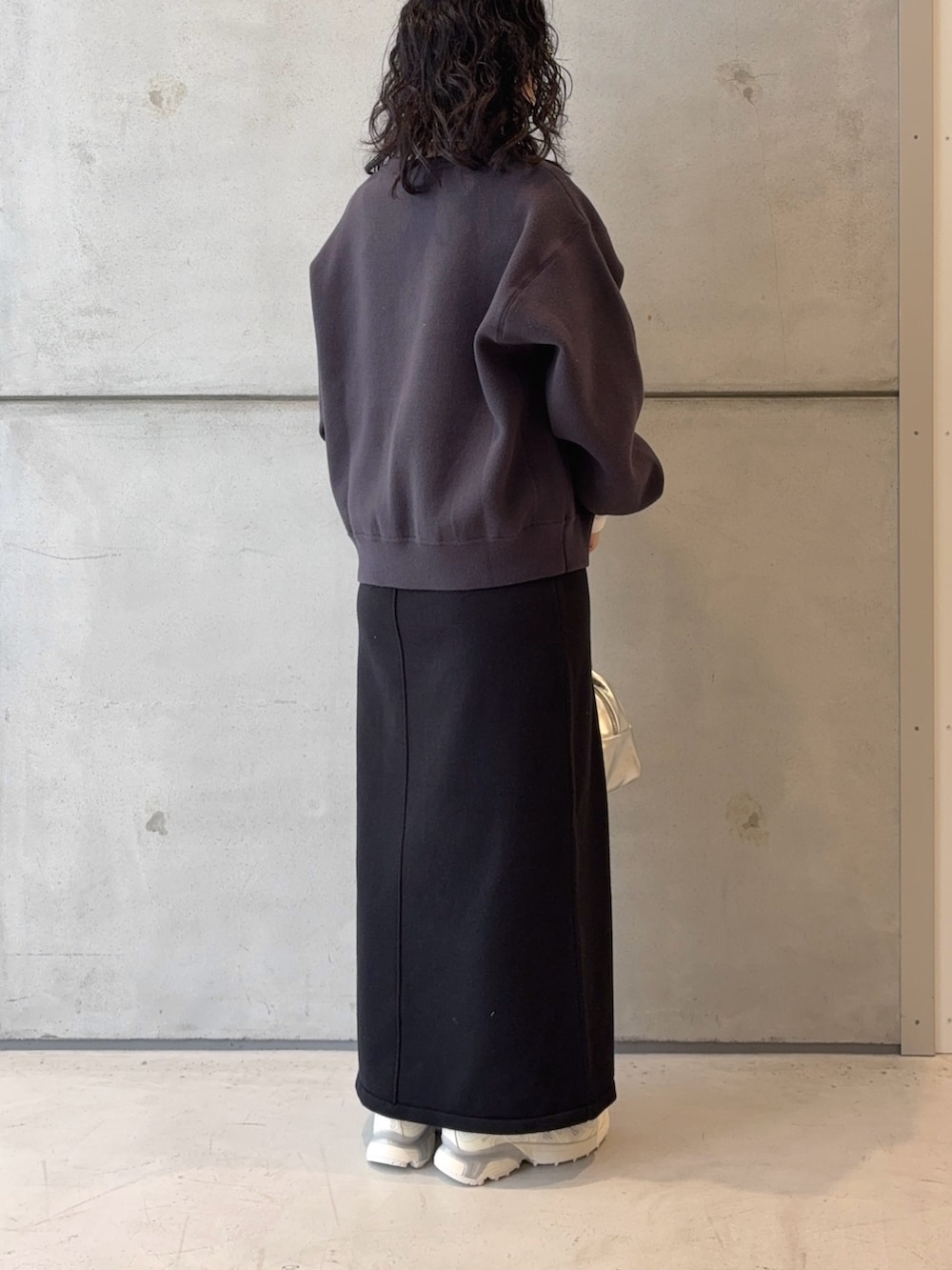 シルバー系のボストンバッグ、ブラック系のスカート、ホワイト系のスニーカーを着用したレディースの秋コーディネートの4枚目の写真