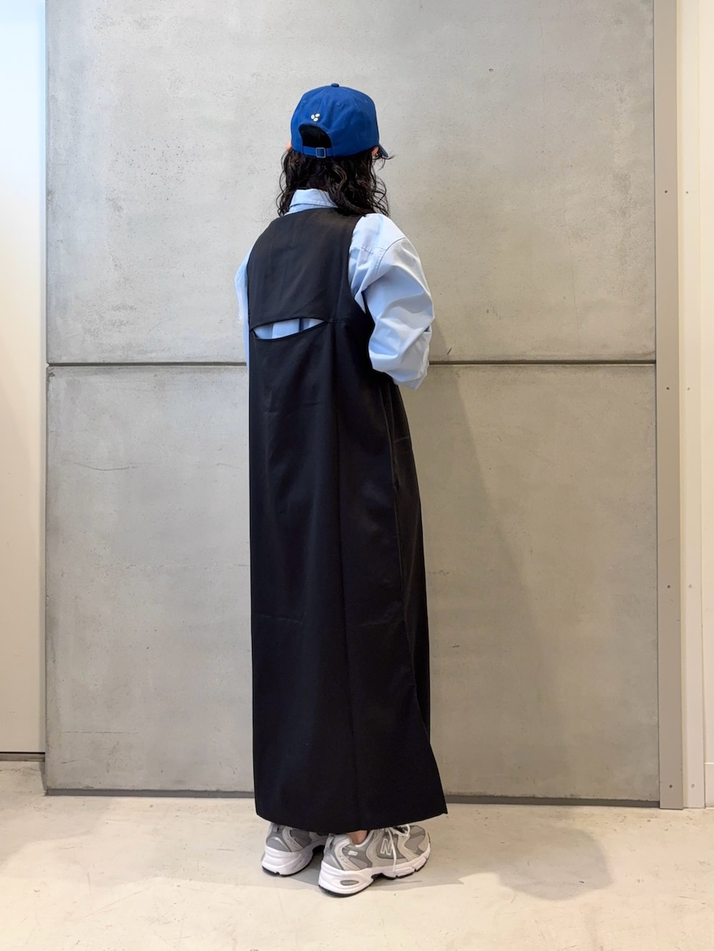 グレー系のスニーカー、ホワイト系のショルダーバッグ、ブラック系のワンピースを着用したレディースの春コーディネートの4枚目の写真