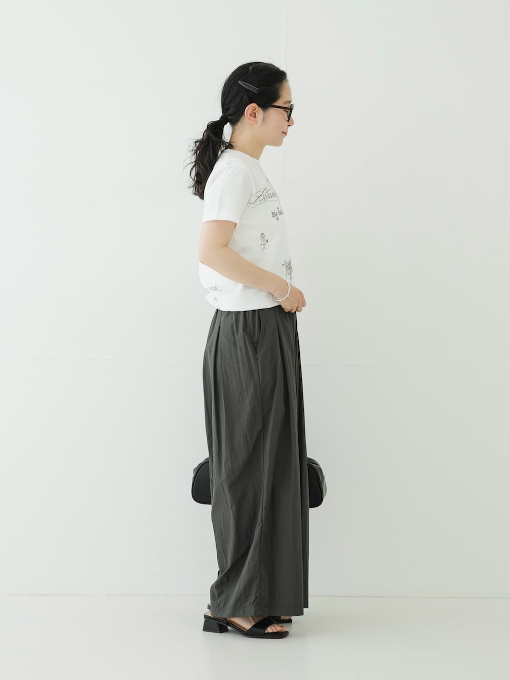 ホワイト系のTシャツ/カットソー、グレー系のその他パンツ、ブラック系のサンダルを着用したレディースの夏コーディネートの3枚目の写真