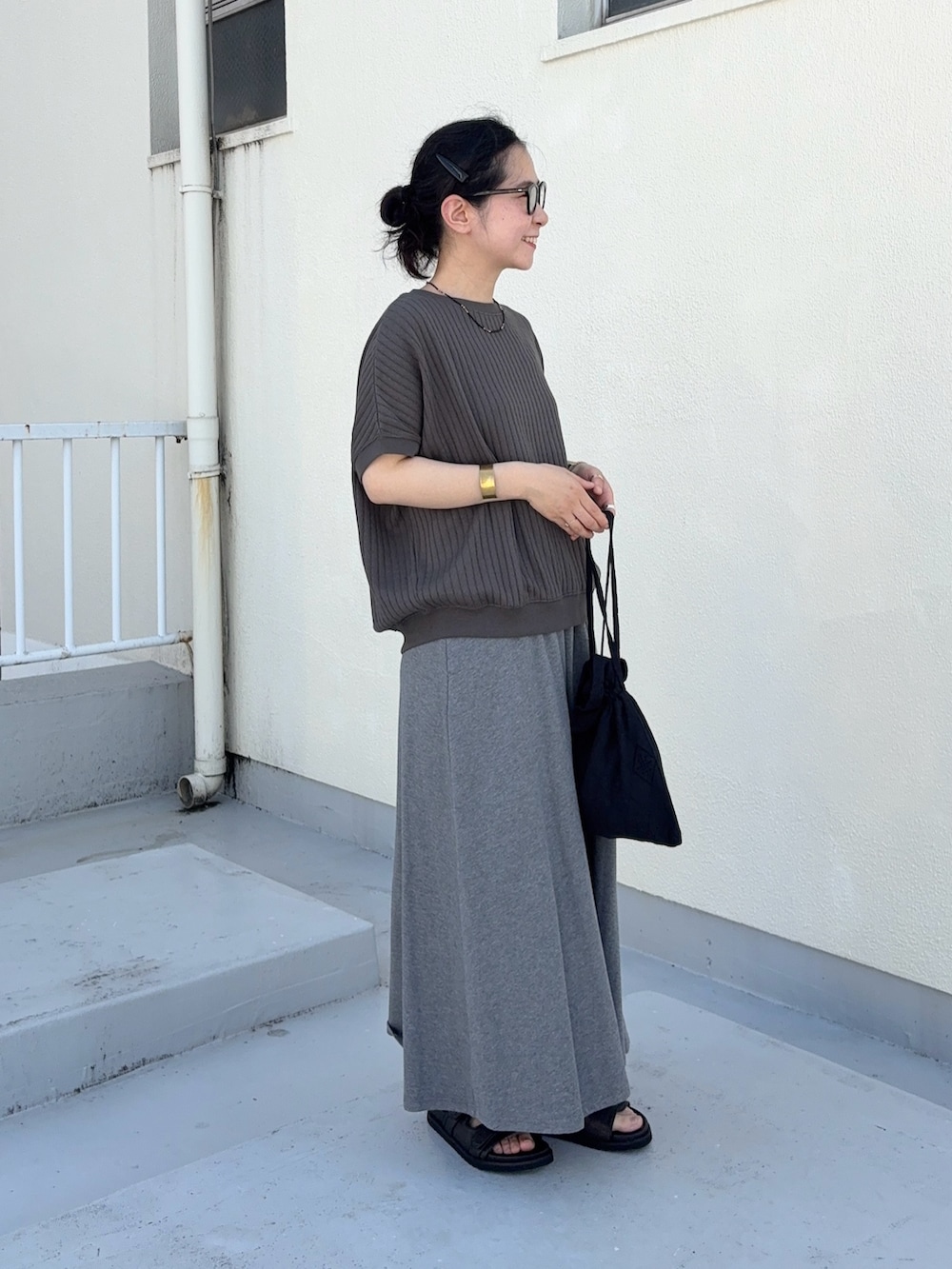 グレー系のTシャツ/カットソー、グレー系のスカート、ブラック系のサンダルを着用したレディースの夏コーディネートの2枚目の写真