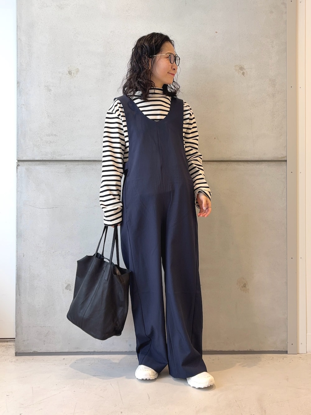 ブラック系のトートバッグ、ホワイト系のTシャツ/カットソー、ホワイト系のスニーカーを着用したレディースの秋コーディネートの2枚目の写真