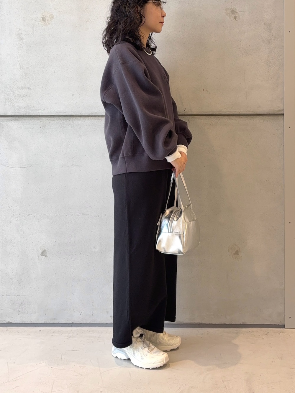 シルバー系のボストンバッグ、ブラック系のスカート、ホワイト系のスニーカーを着用したレディースの秋コーディネートの3枚目の写真