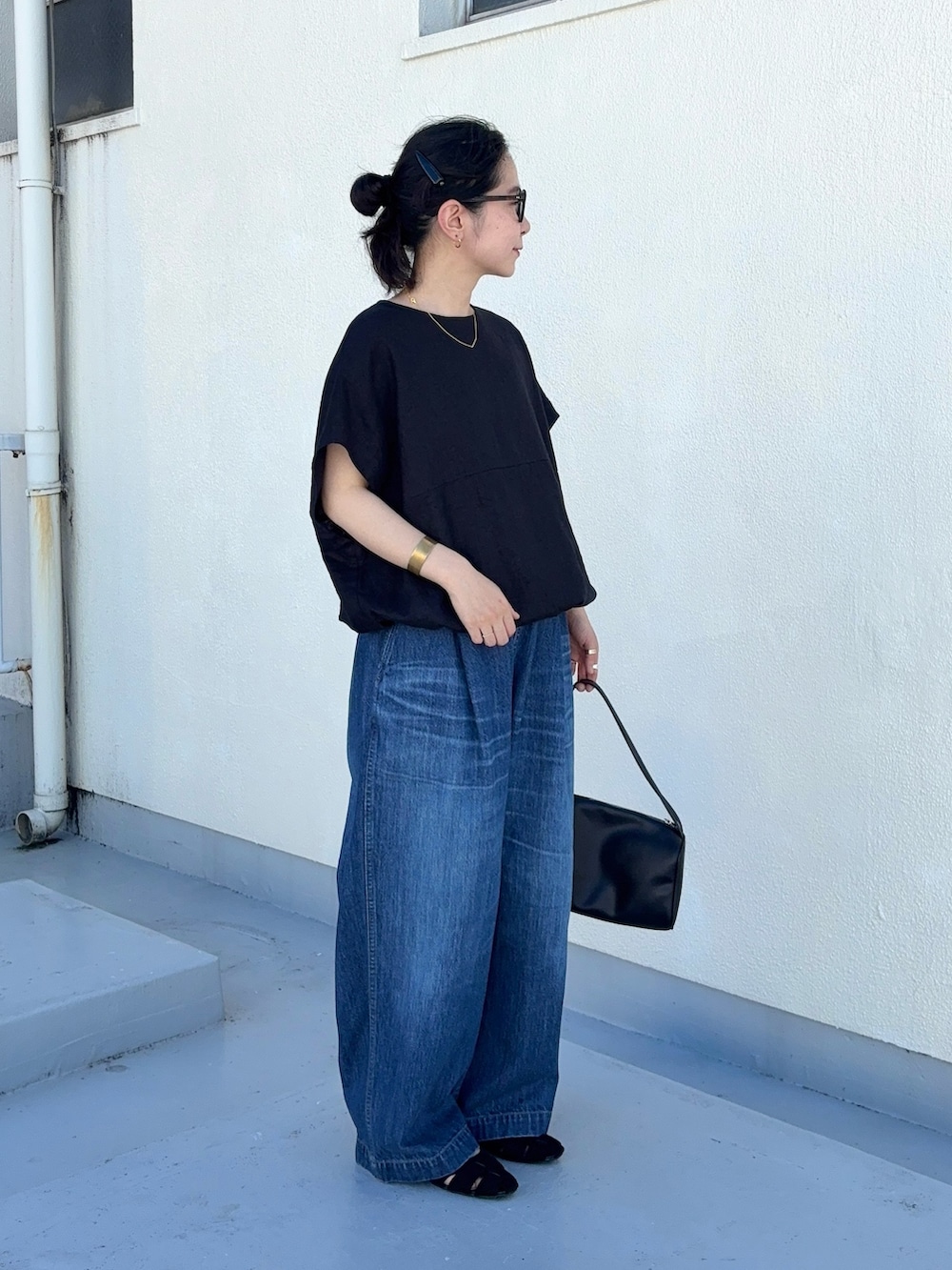 ブルー系のデニムパンツ、ブラック系のパンプス、ブラック系のハンドバッグを着用したレディースの夏コーディネートの3枚目の写真