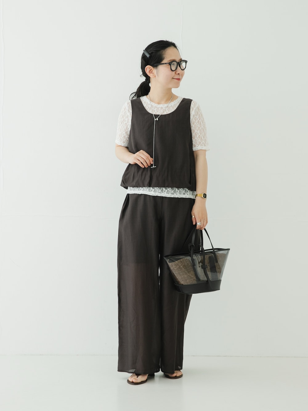 グレー系のその他パンツ、ブラウン系のサンダル、ブラック系のかごバッグを着用したレディースの夏コーディネートの2枚目の写真