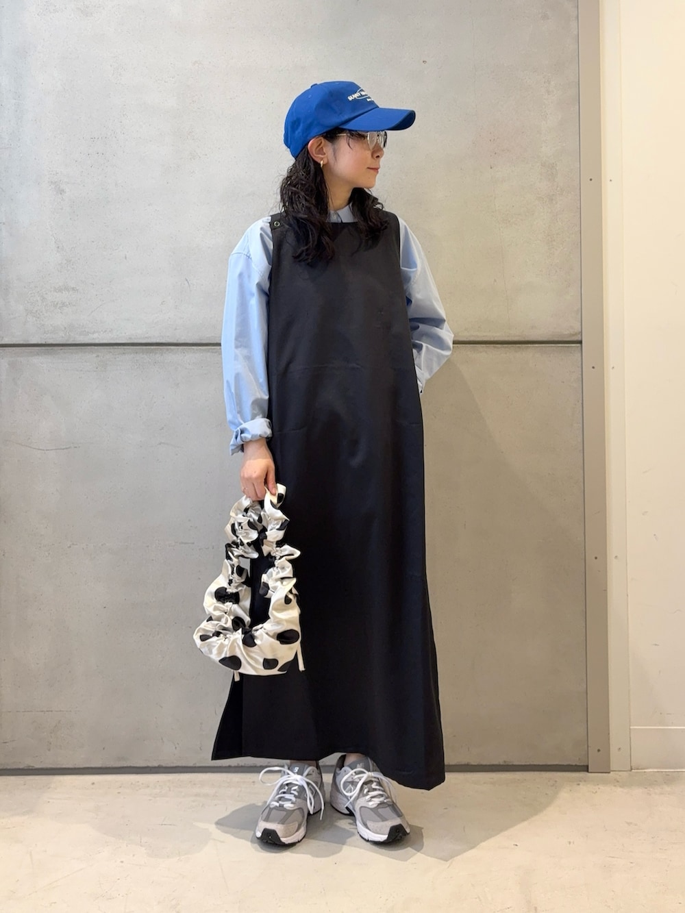 グレー系のスニーカー、ホワイト系のショルダーバッグ、ブラック系のワンピースを着用したレディースの春コーディネートの2枚目の写真