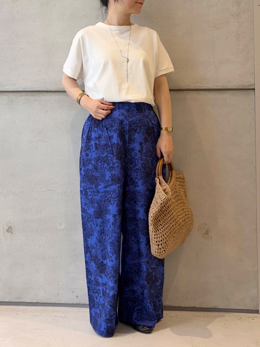 ベージュ系のトートバッグ、ブラック系のパンプス、ホワイト系のTシャツ/カットソーを着用したレディースの夏コーディネートの2枚目の写真