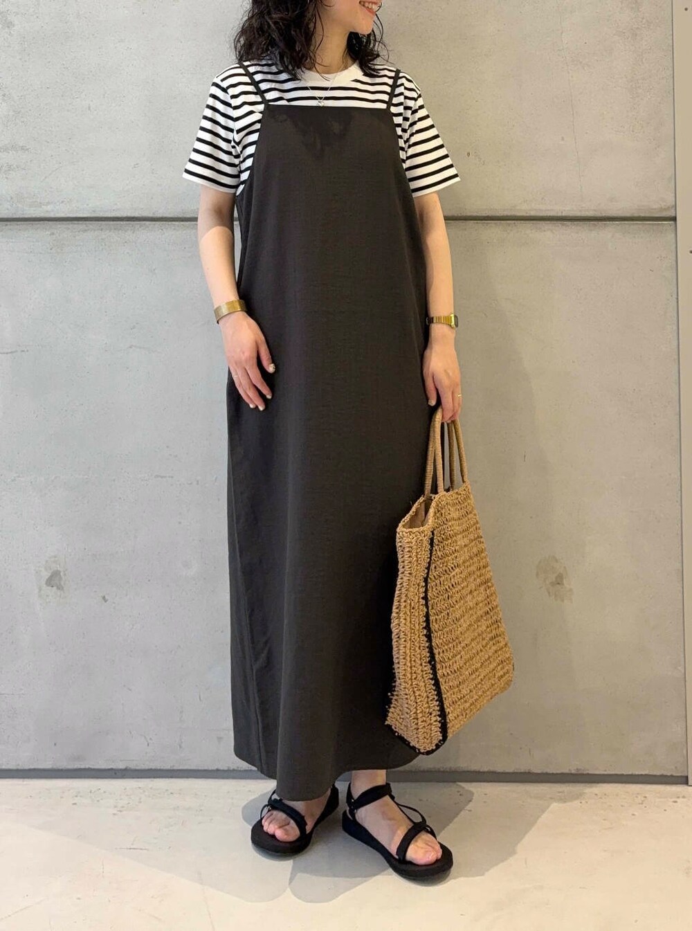 ベージュ系のトートバッグ、ホワイト系のTシャツ/カットソー、ブラック系のサンダルを着用したレディースの夏コーディネートの2枚目の写真