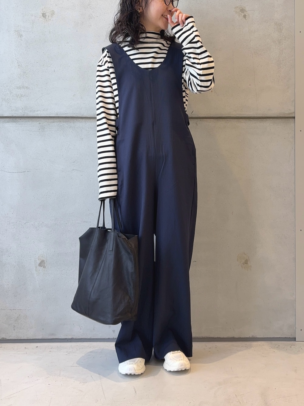 ブラック系のトートバッグ、ホワイト系のTシャツ/カットソー、ホワイト系のスニーカーを着用したレディースの秋コーディネートの3枚目の写真