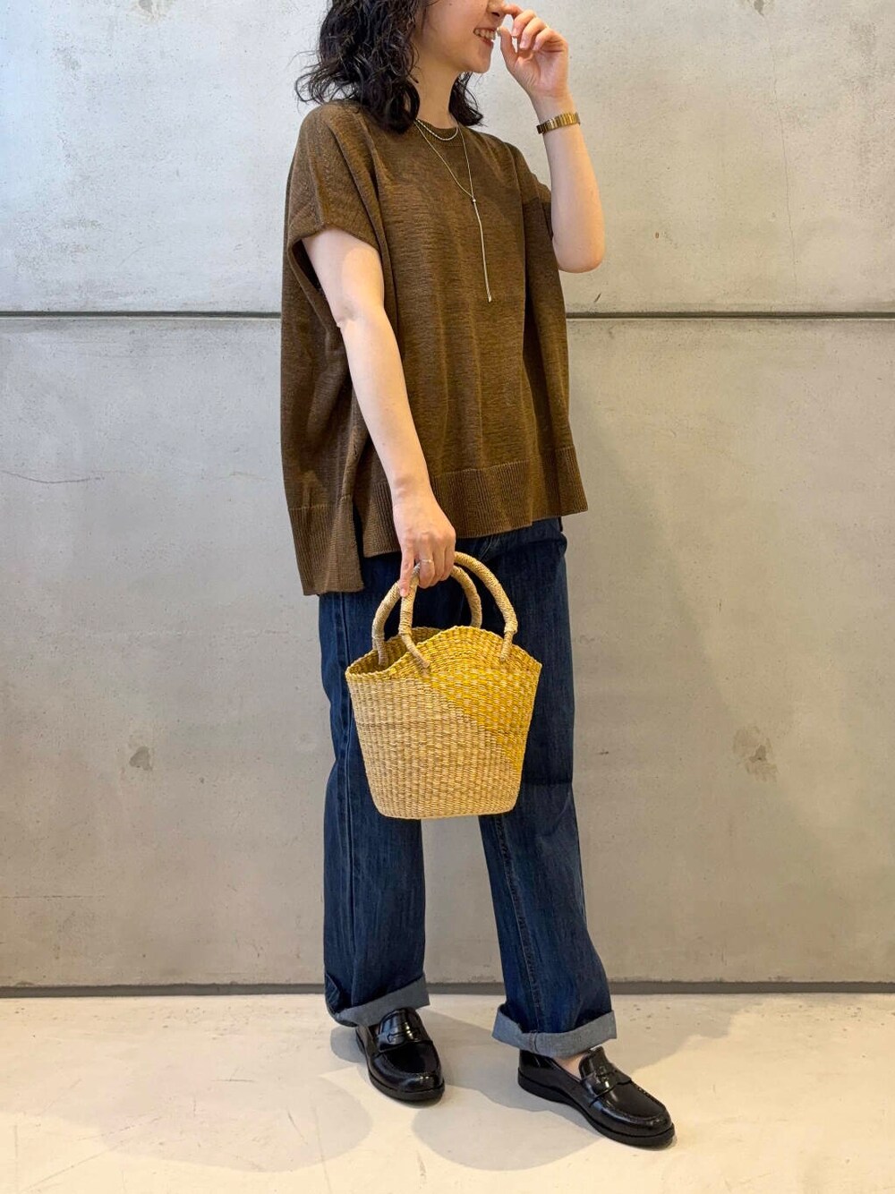 イエロー系のショルダーバッグ、ブルー系のデニムパンツ、ブラウン系のニット/セーターを着用したレディースの夏コーディネートの3枚目の写真