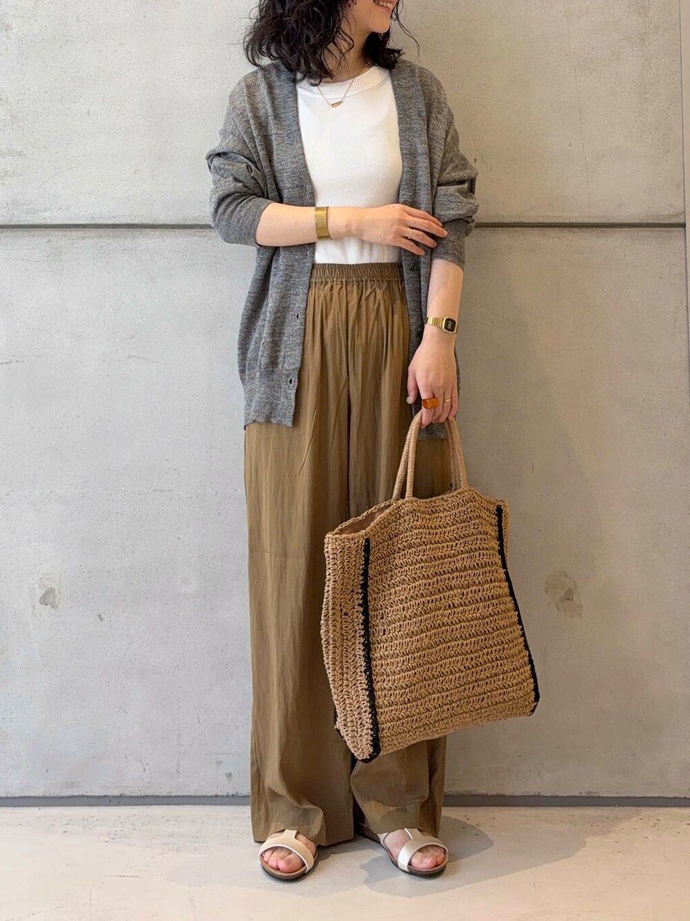 グレー系のカーディガン/ボレロ、ベージュ系のトートバッグ、ホワイト系のタンクトップを着用したレディースの夏コーディネートの2枚目の写真