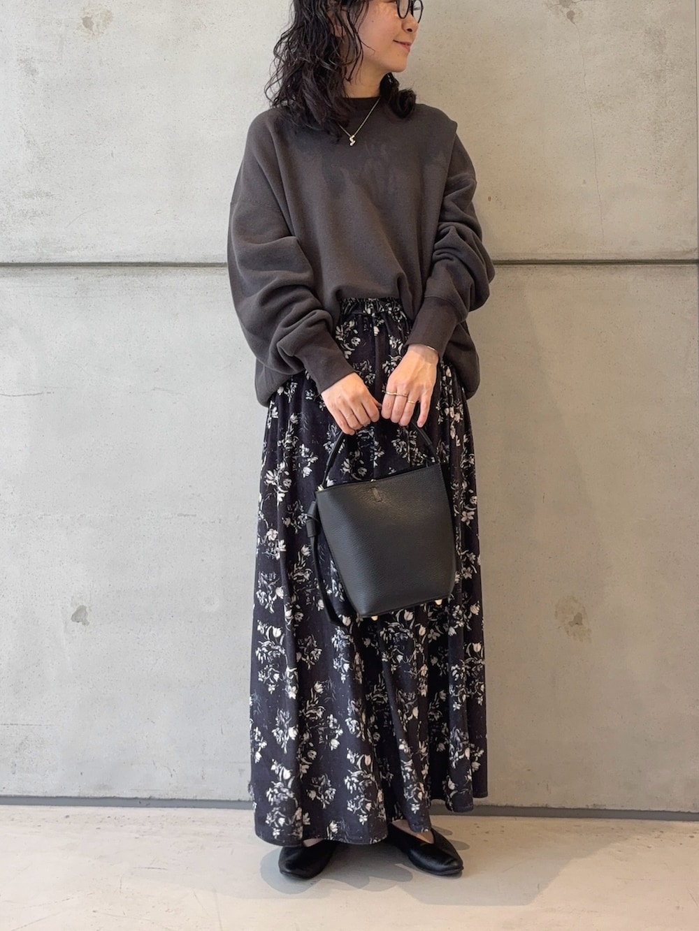 グレー系のスウェット、ブラック系のハンドバッグ、ブラック系のパンプスを着用したレディースの秋コーディネートの2枚目の写真